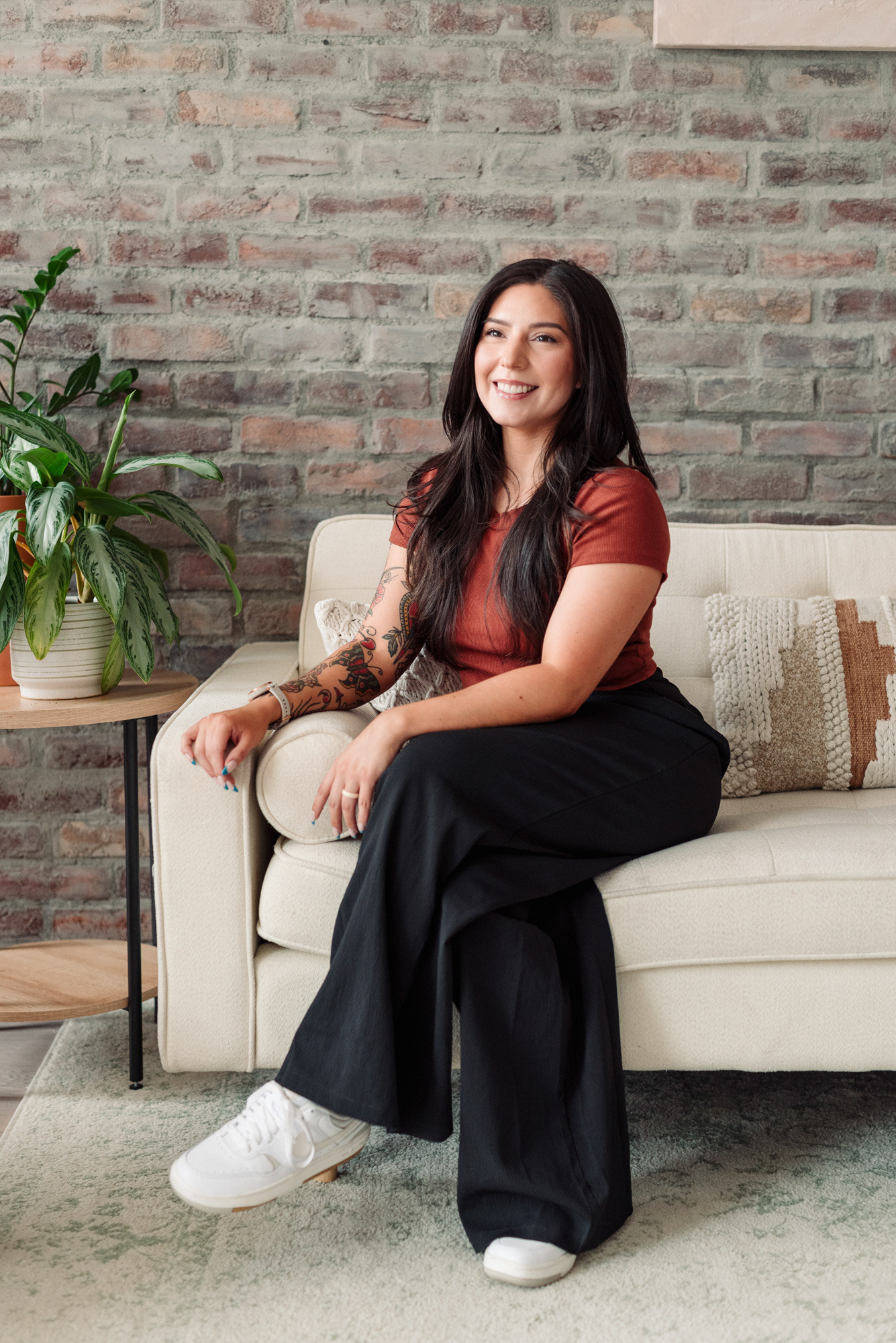 Branding photograph of a personal trainer in Colorado Springs sitting on a white sofa.