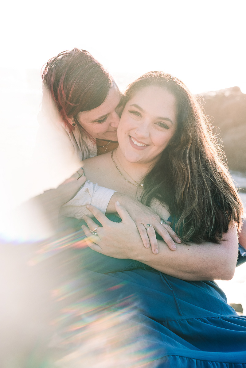 Portrait of a couple embracing with a colorful lens flare.
