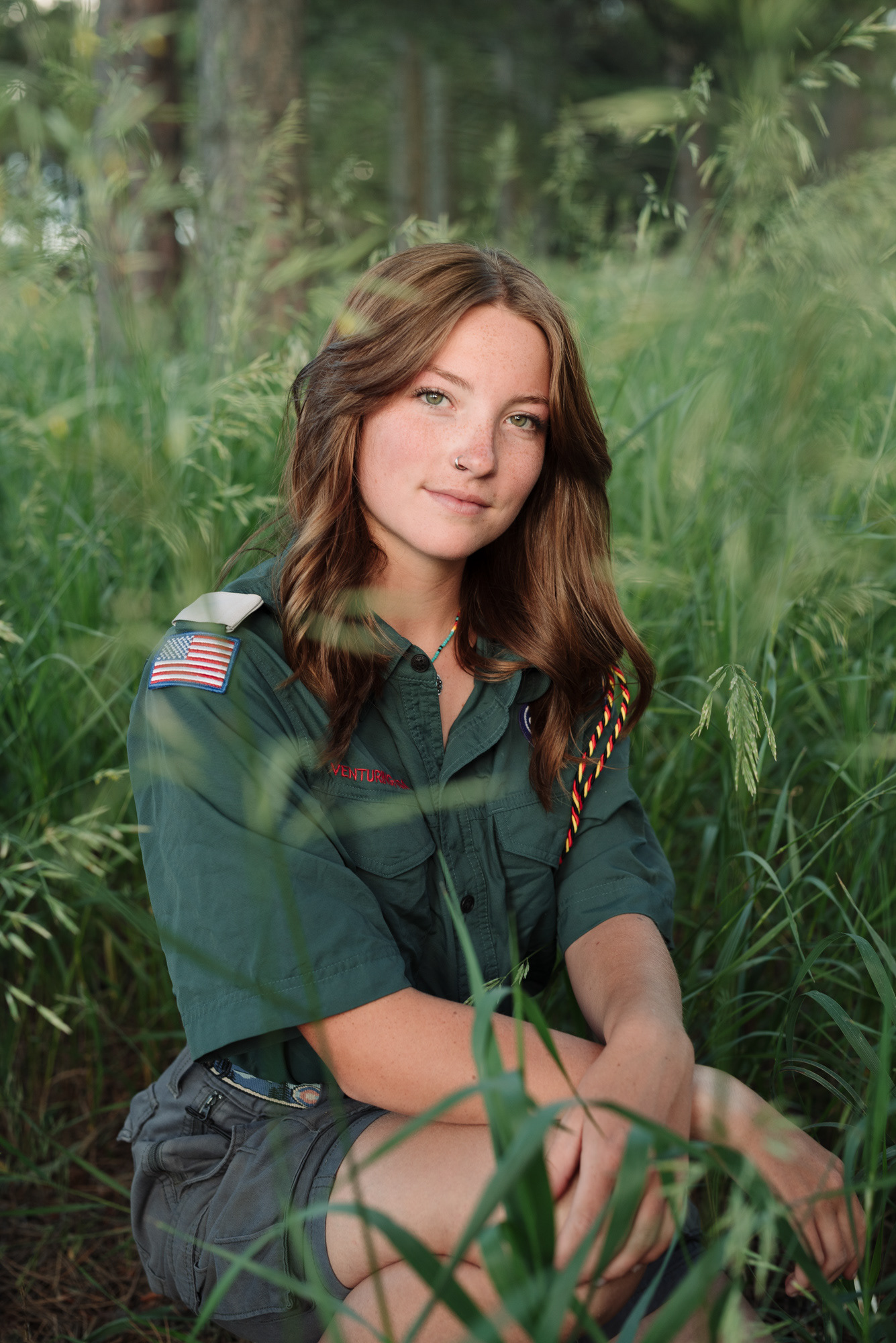 High school senior portrait of a girl in a scouts uniform among grasses.