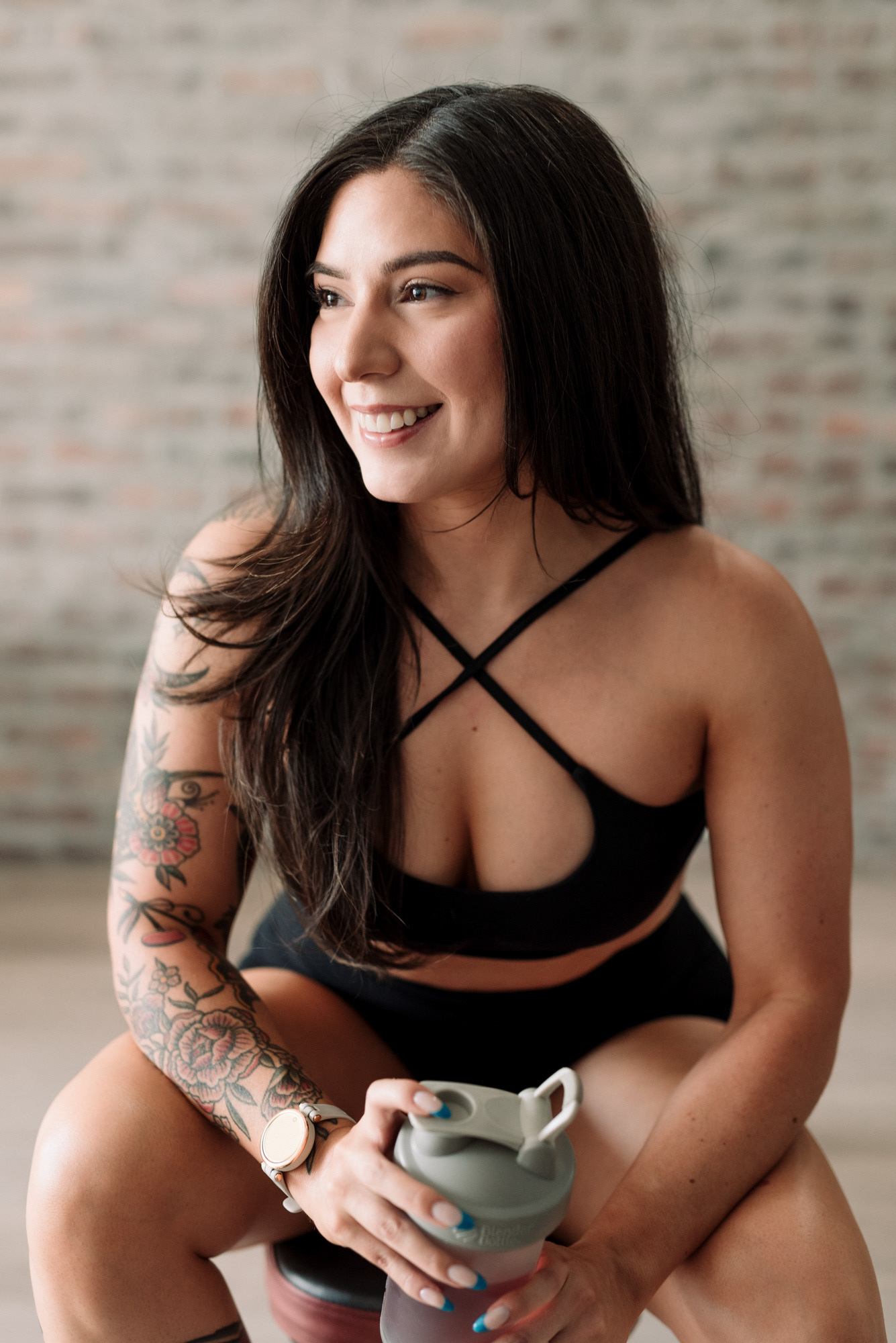 Branding photograph of a personal trainer with tattoos taking a break from her workout.