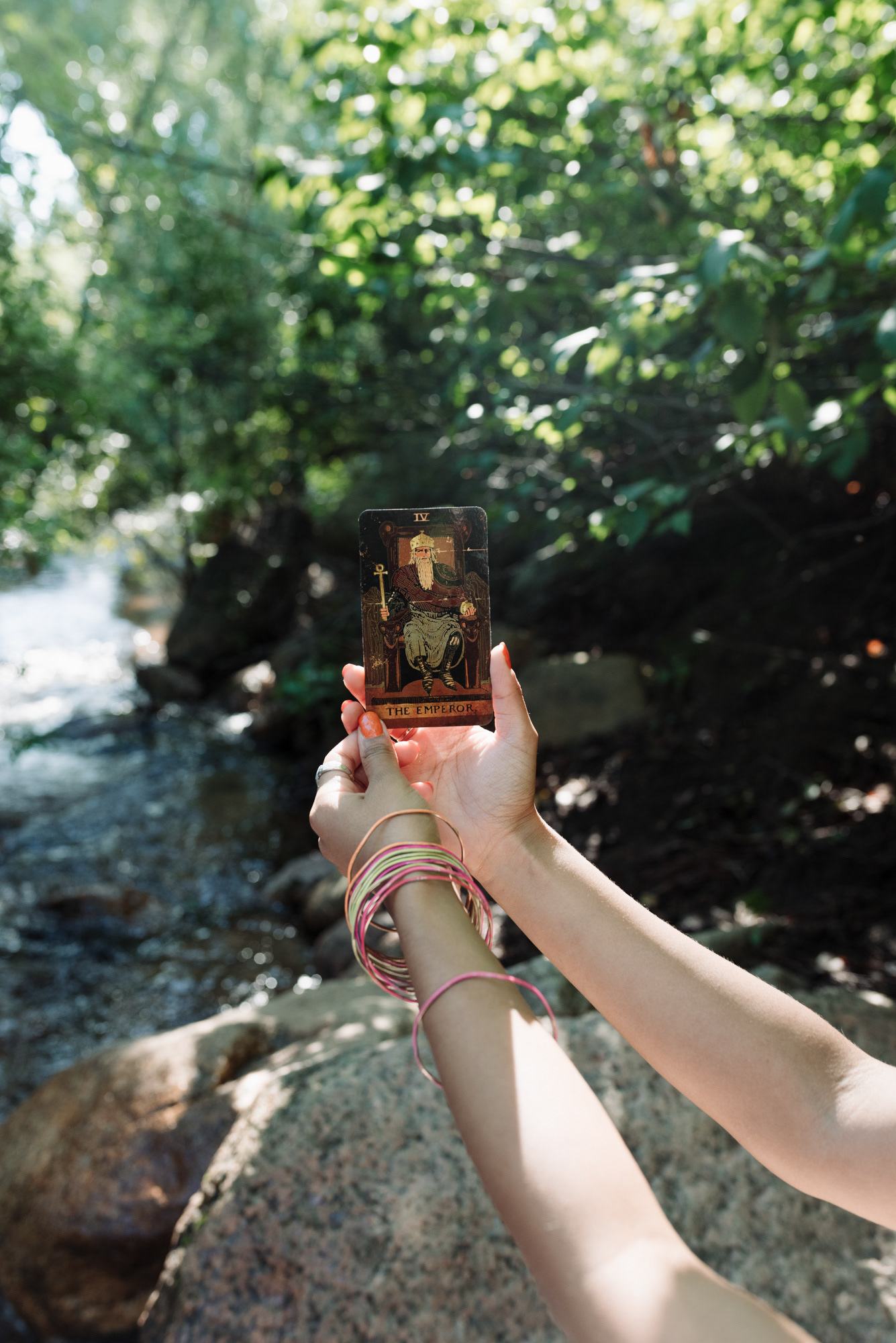Woman holding up The Emperor tarot card.