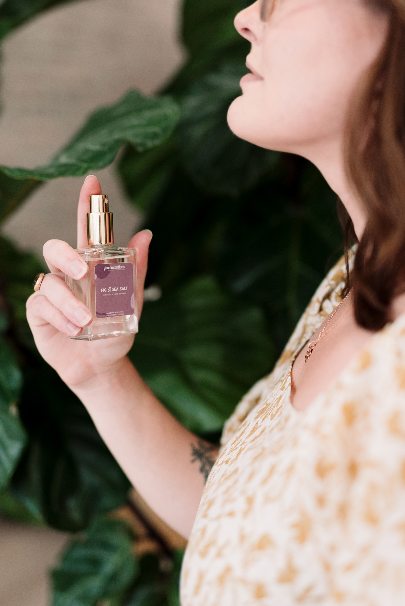 Portrait of a woman spraying perfume on her neck.