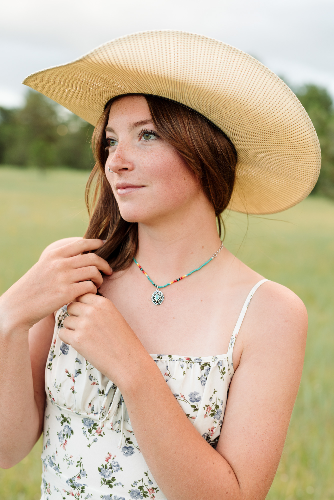 Senior portrait photograph of a girl in a cowboy hat and a summer dress.
