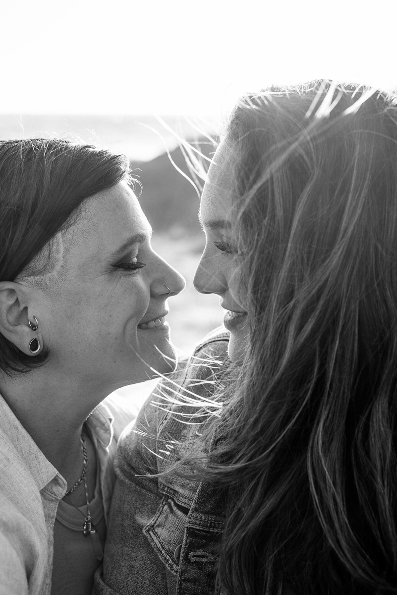 Portrait of two women looking lovingly at each other with hair blowing in the wind.