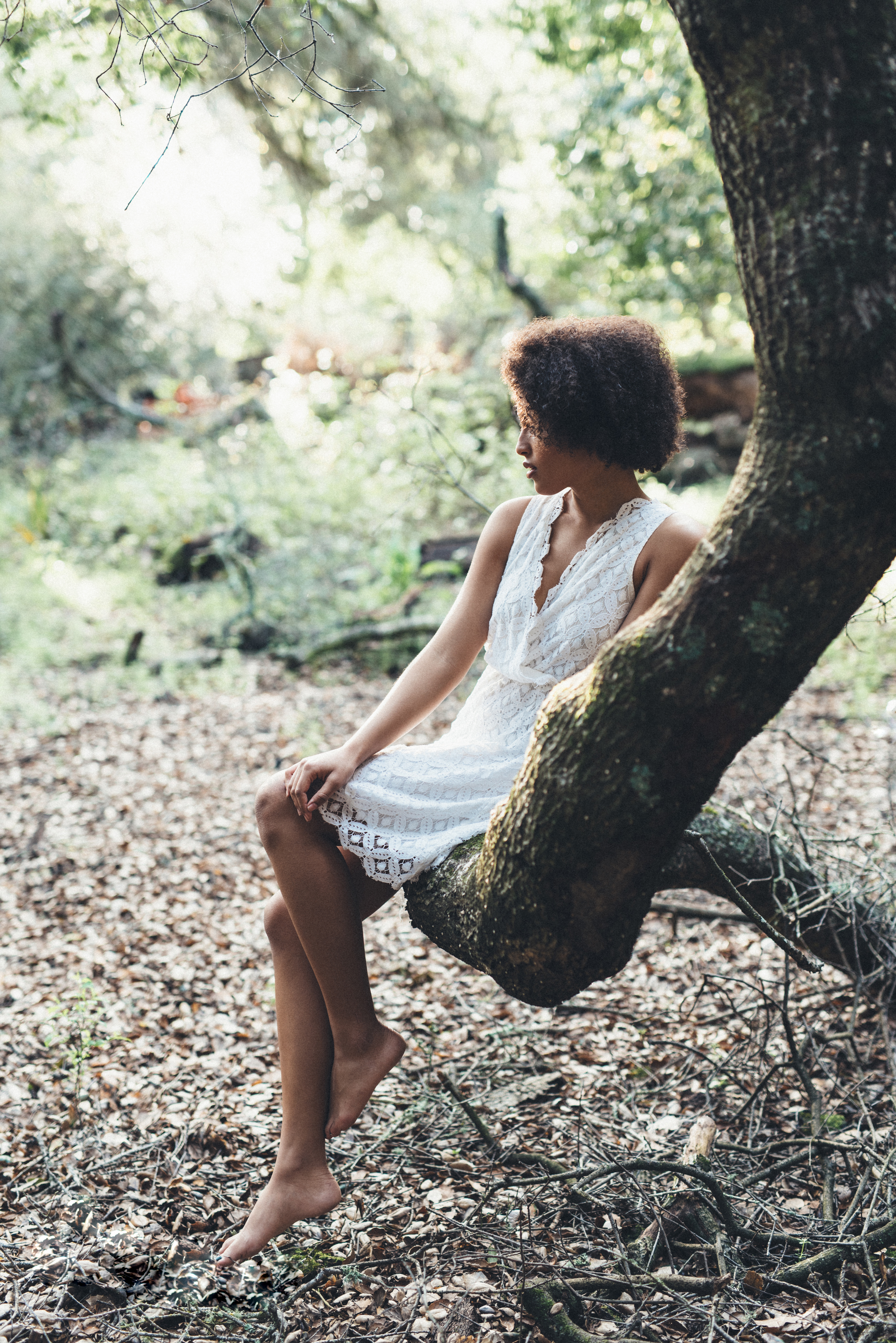 Beautiful senior woman sitting in a tree for her senior photoshoot.