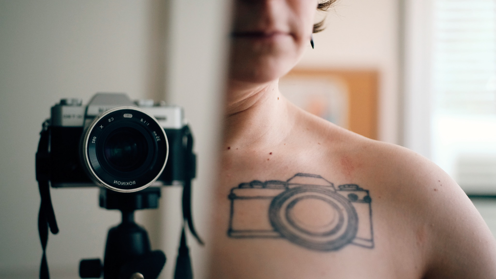 Image description: The mirror reflection of Sami topless with her camera tattoo shown. The camera was in the picture too.