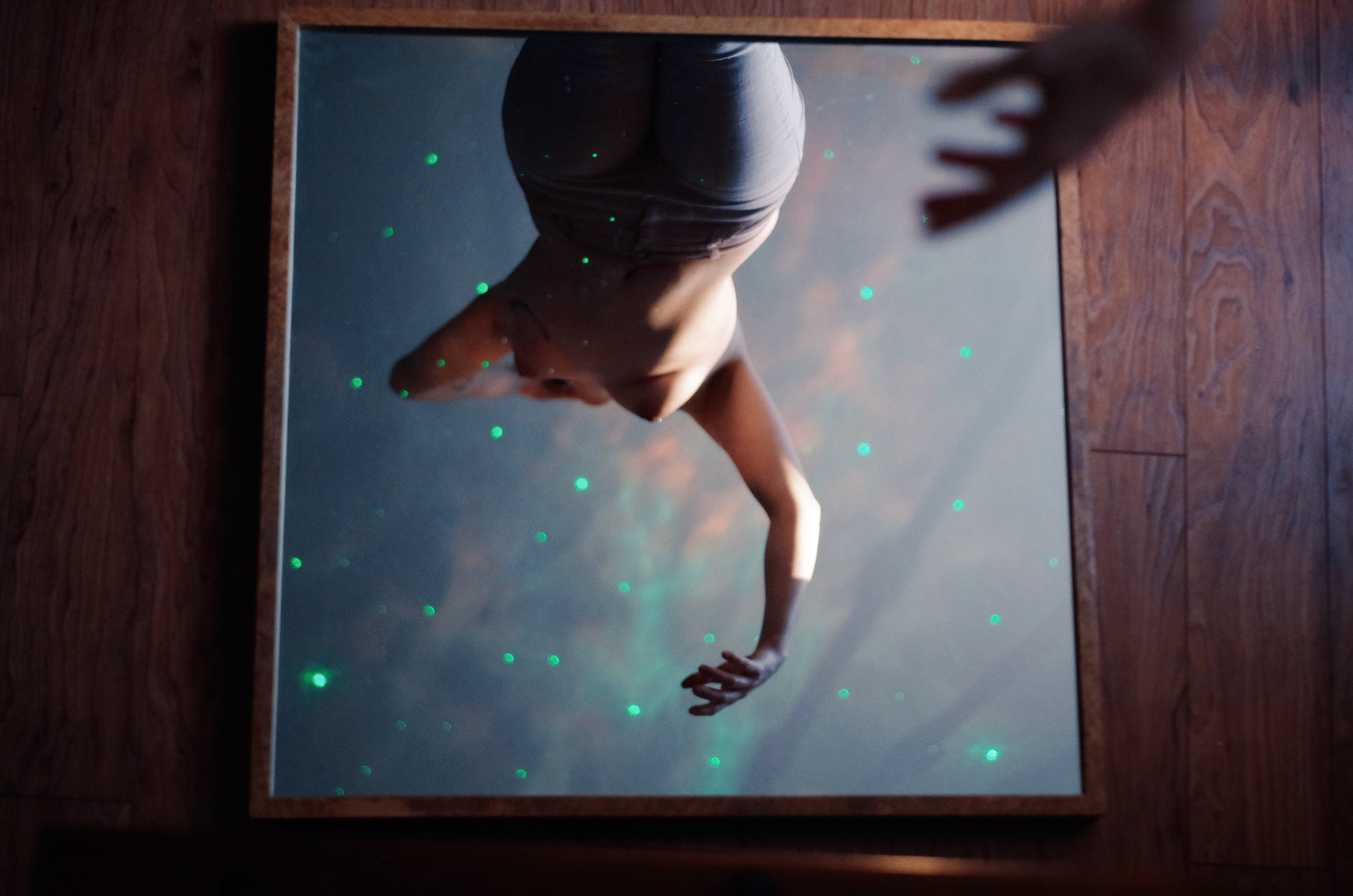 Image description: Sami was topless with the jeans in her room. The angle was through the mirror on the floor while there was a galaxy projector on the ceiling. 