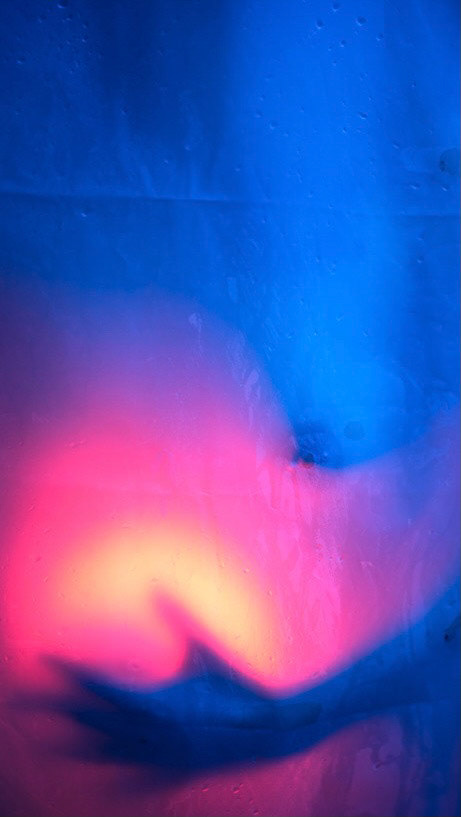 Image description: the close-up of Sami's nipple behind the shower curtain. She was holding the light hue. It was a pink and yellow against the blue.