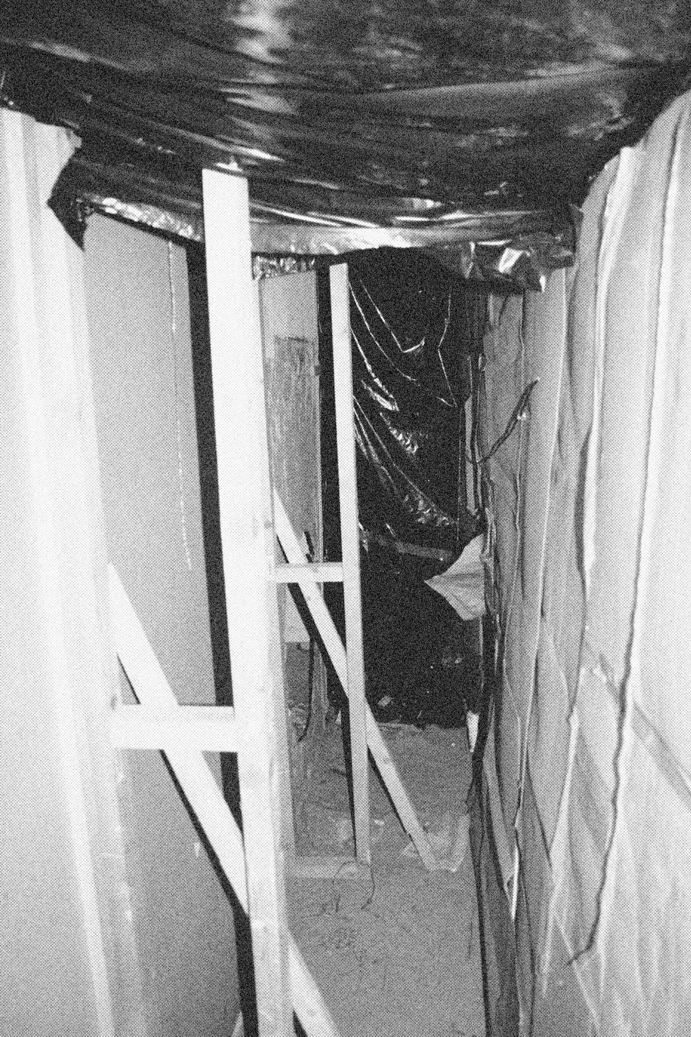 Reconstructed Constructioninstallationcardboard on wooden construction, silk screened wallpaper, tiled floor, carpet floor, electrical equipment: television, DVD-player, transmitter, lightning, plastic ridge tent, silkscreen materials, copy prints, iron case, bed mattress, buckets of latex paint.2006