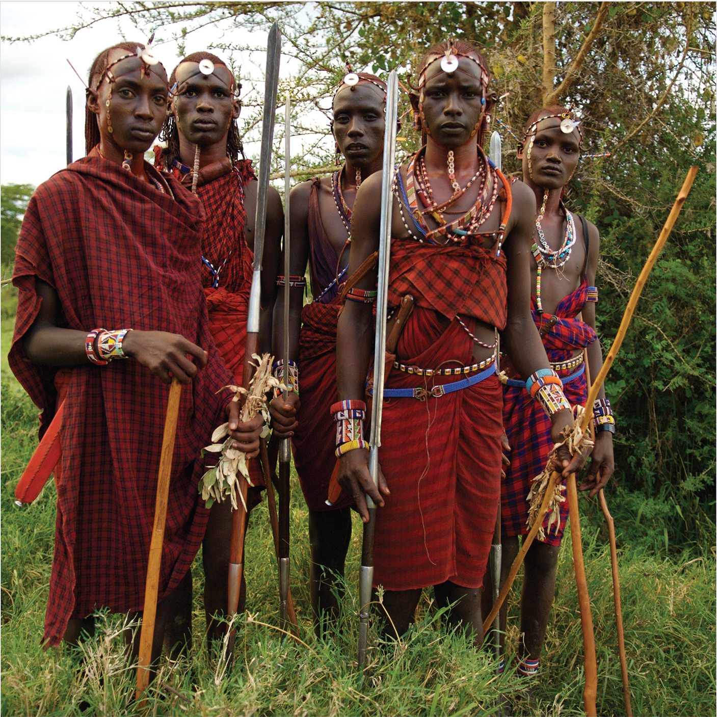 Group of Maasai warriors in ceremonial dress with spears and swords, Through Maasailand.