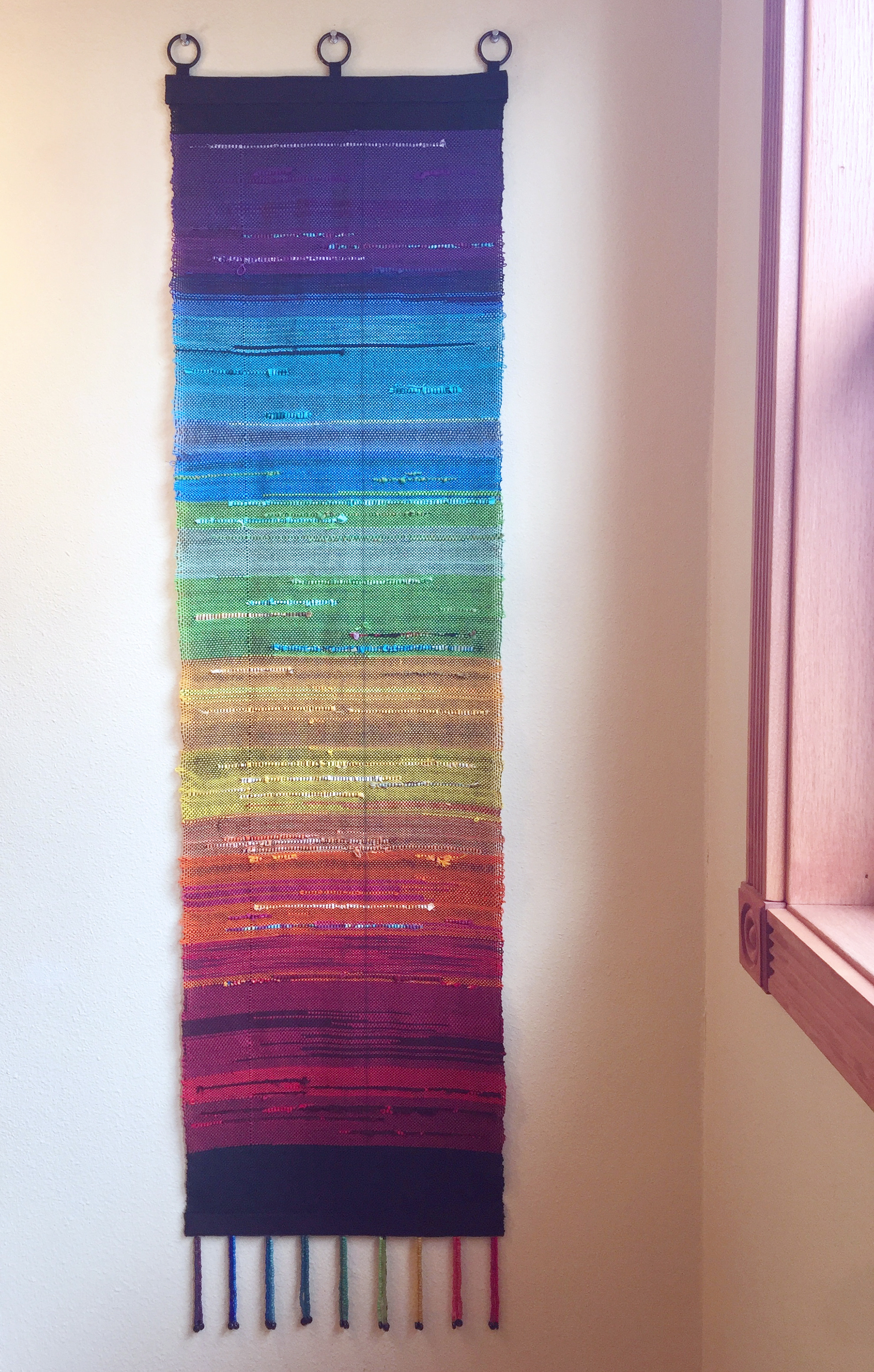 "One Love," handwoven wall piece with beaded fringe.