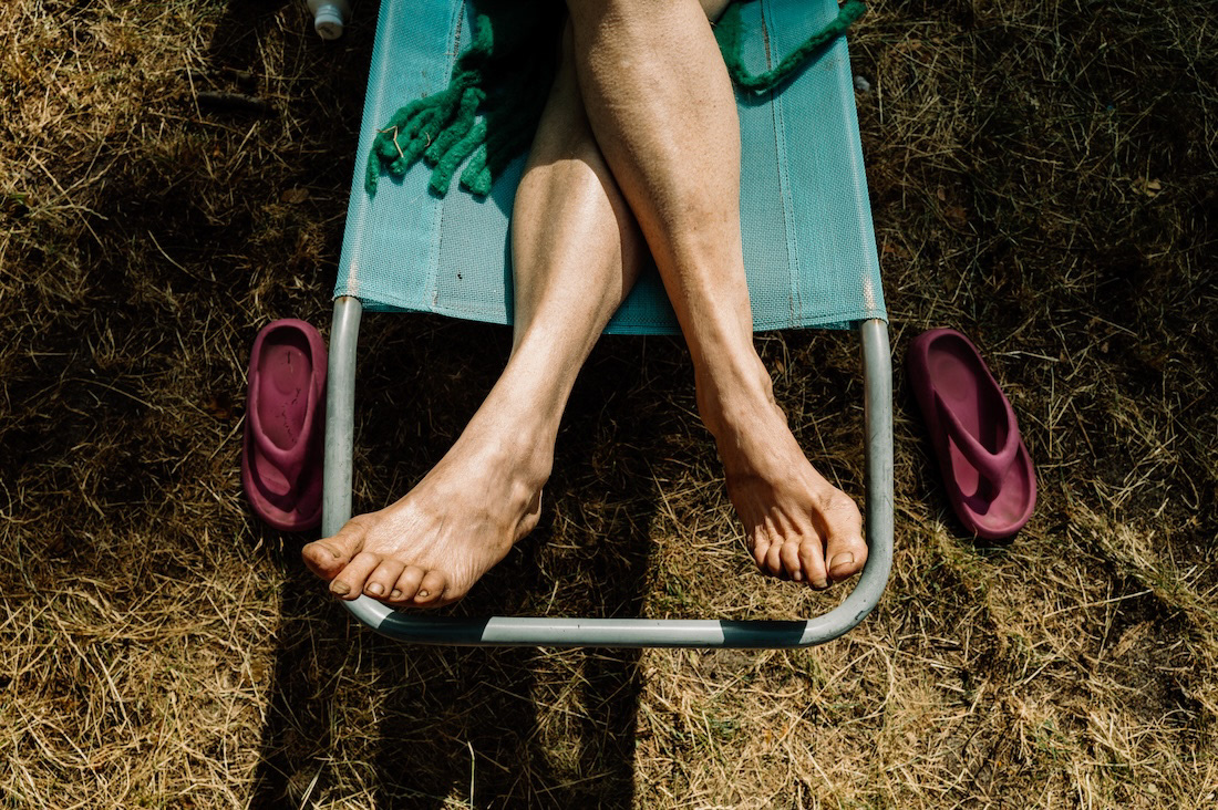 Bare feet standing on a wooden pier by the lake, from the project Only in Summer