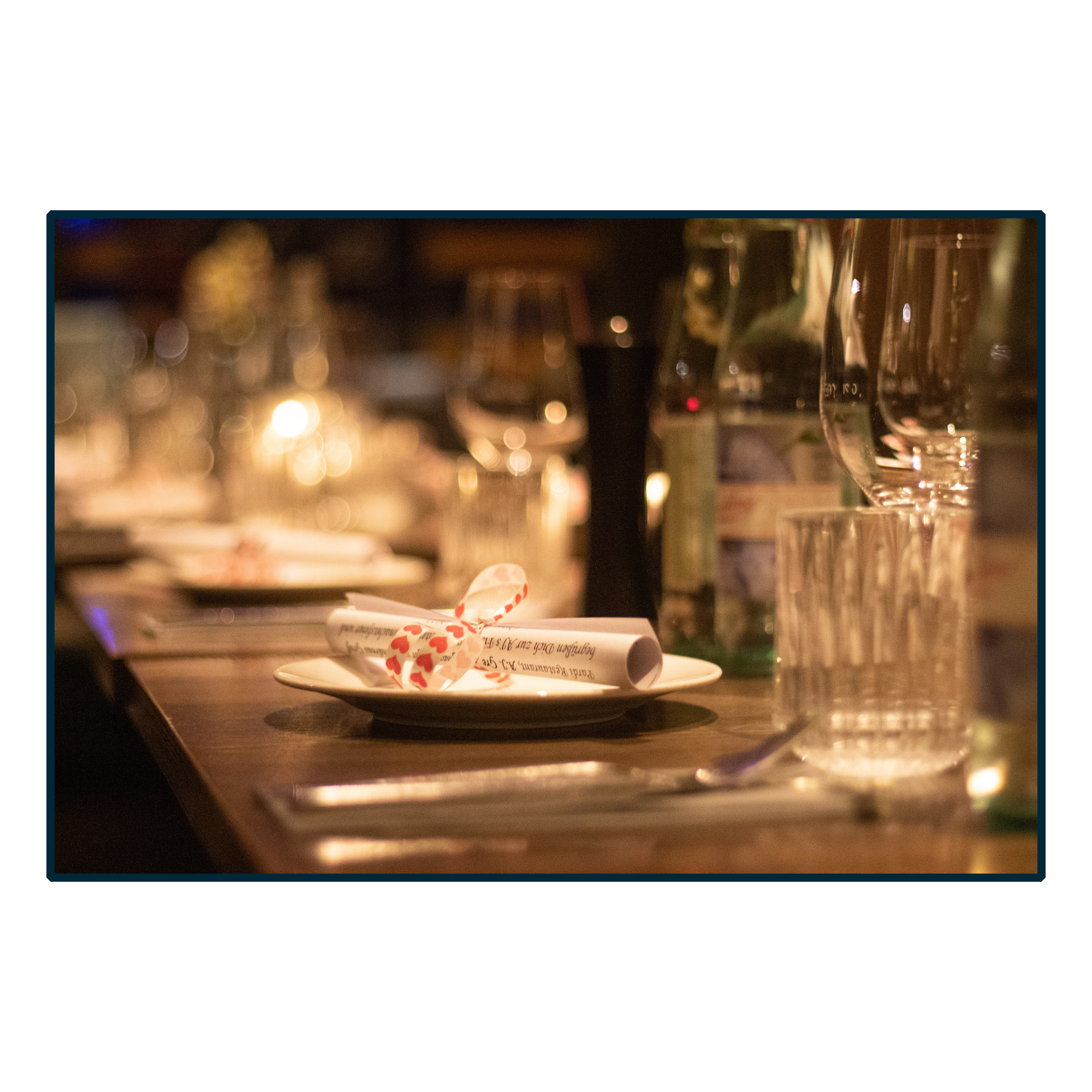 Teller, Besteck, Glas und Einladung auf Tisch mit schöner Anrichtung in einem Restaurant, Eventfotografie