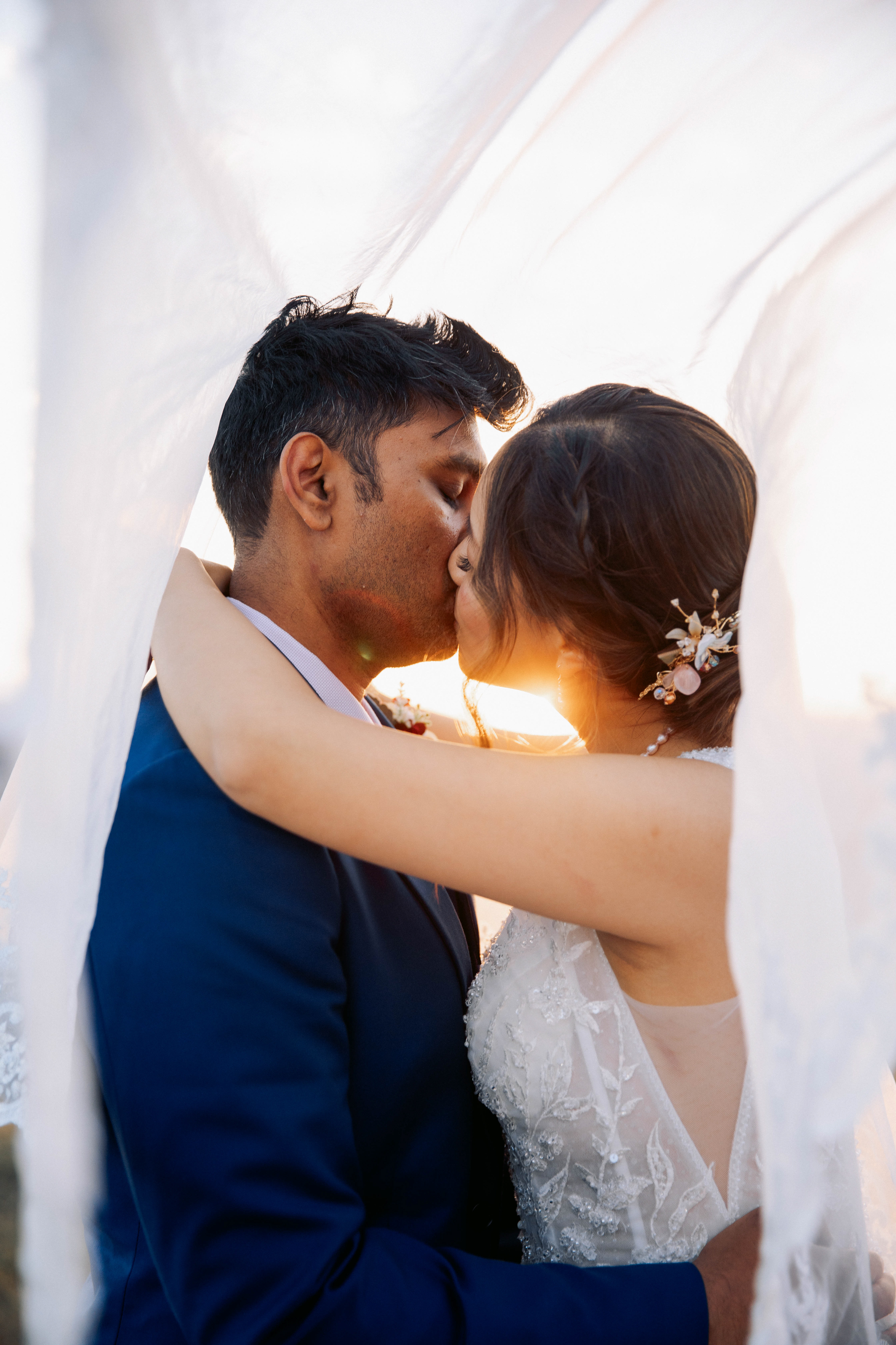 Romantic wedding photo of couple kissing under the veil during sunset in Canberra, captured by Olia Photography