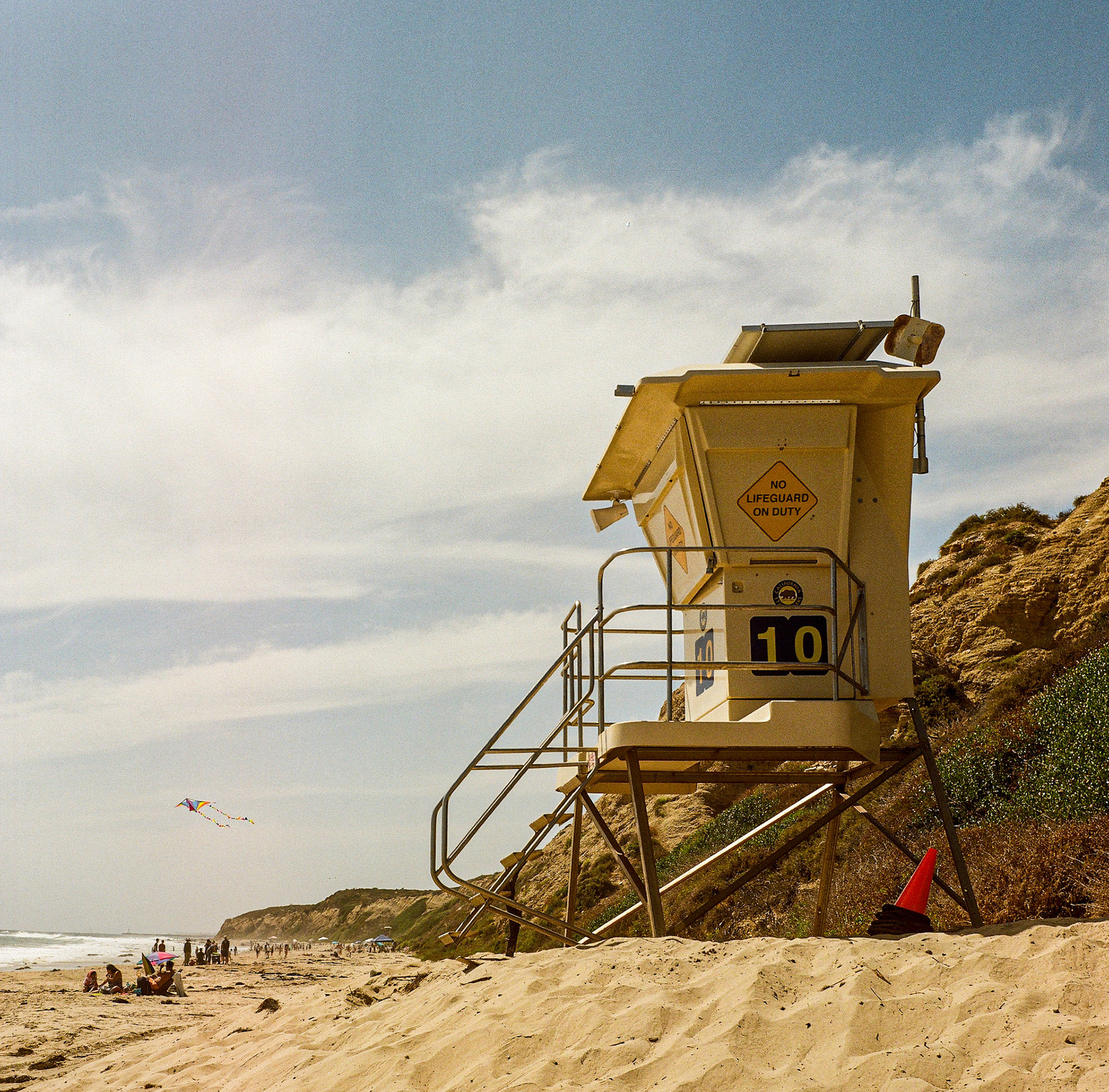 Lifeguard tower overlooking a quiet beach with soft coastal haze and warm sunlight on analog film. Explore the full series at dyoon.space.