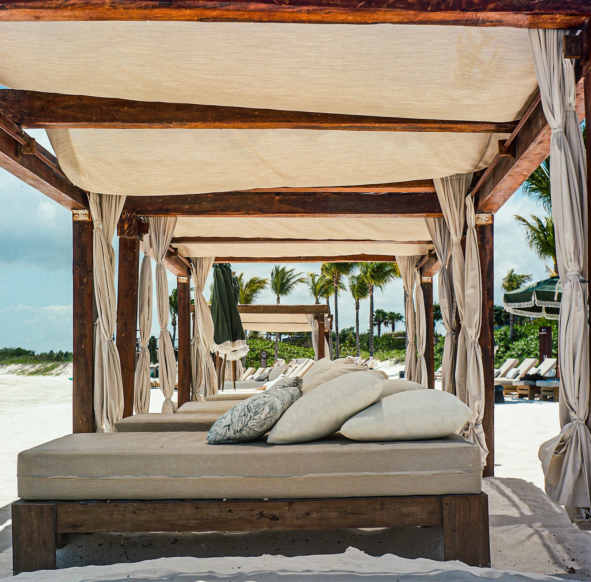 Luxury beach cabana with flowing curtains and oceanfront relaxation space in soft natural light. Explore the full series at dyoon.space.