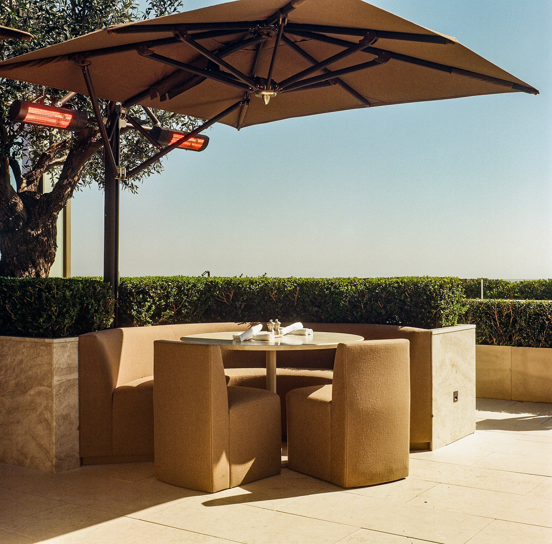 Outdoor lounge seating beneath umbrellas at a luxury resort terrace overlooking the coastline. Explore the full series at dyoon.space.