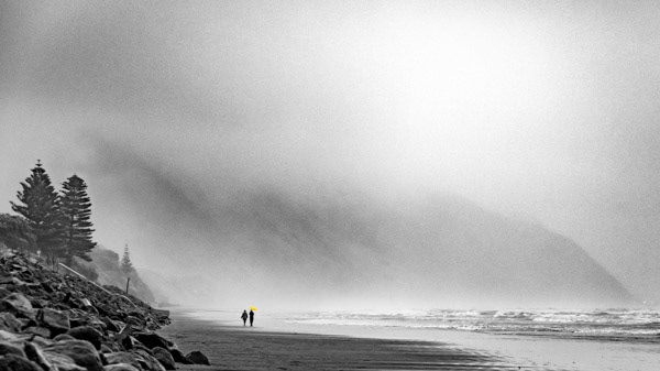 Yellow umbrella: Two women walking on the beach south from Paekākāriki, mirrored by the two Norfolk pines on the left. The dreary day was brightened by the yellow umbrella, in this otherwise monochrome print.