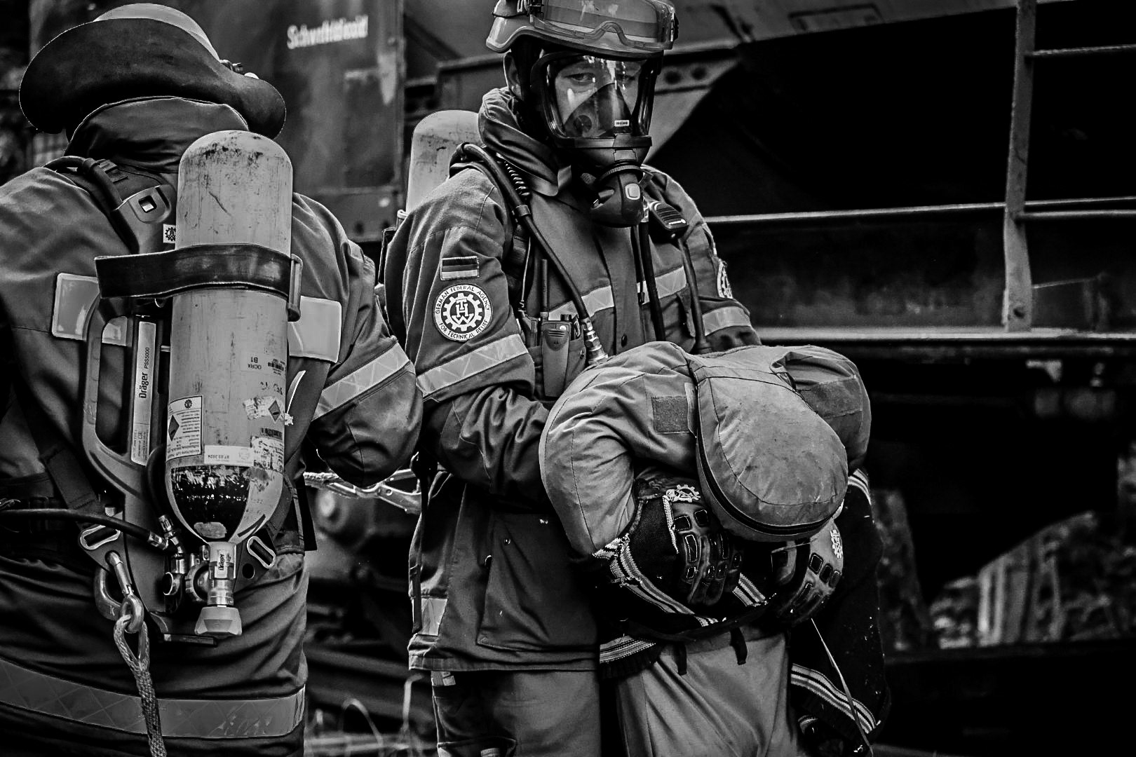 Menschenrettung - die THW-Truppmänner haben unter Atemschutz den Dummy aus einem Kesselwagen gerettet, abgeseilt und transportieren ihn aus dem Gefahrenbereich weg. Bei fast 35°C im Hochsommer zu Mittagszeit. Übung des THW und der Rettungshundestaffeln in Wesel