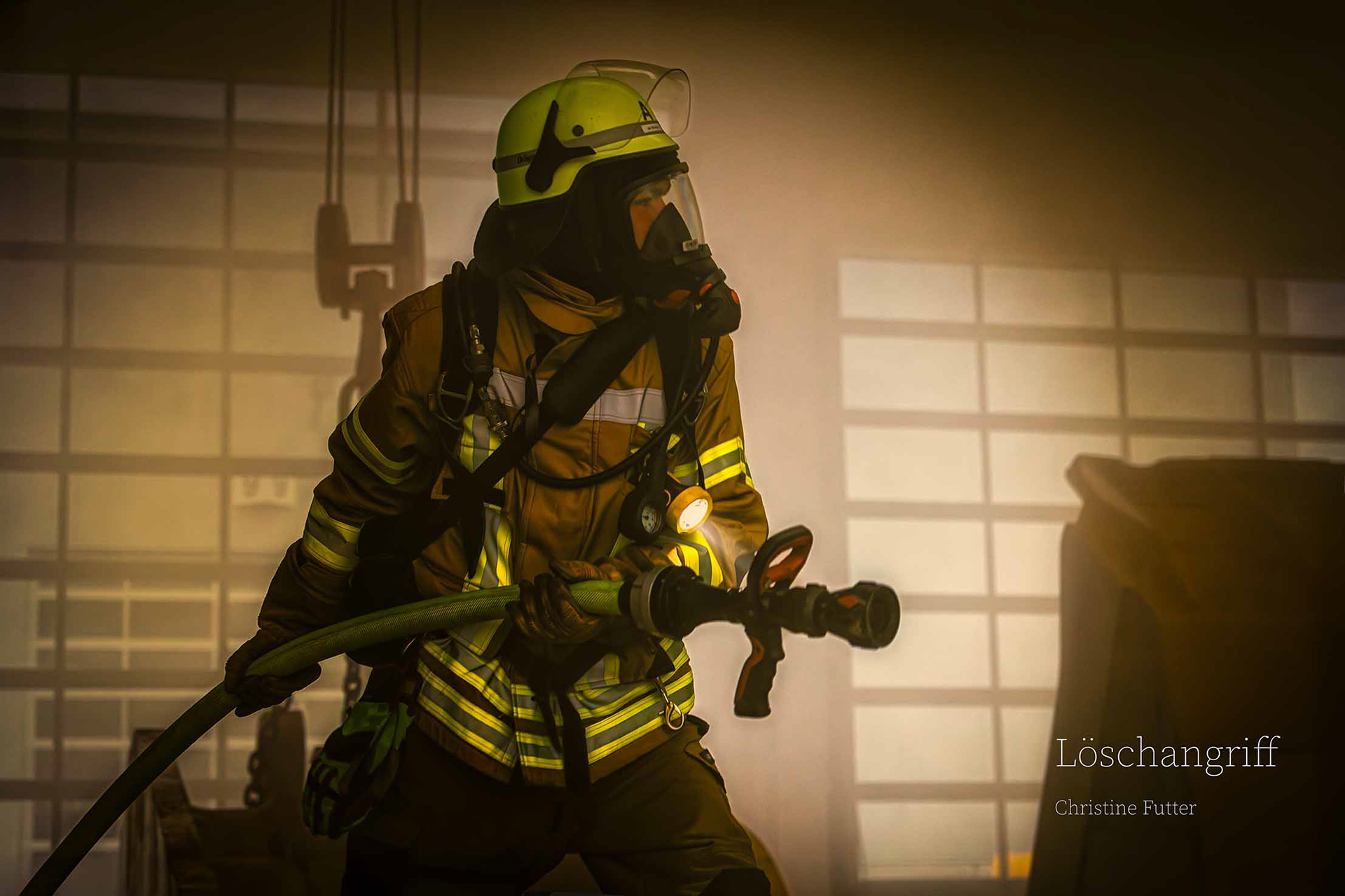 Ein Wehrmann bereitet einen Löschangriff in einer verrauchten Industriehalle vor.