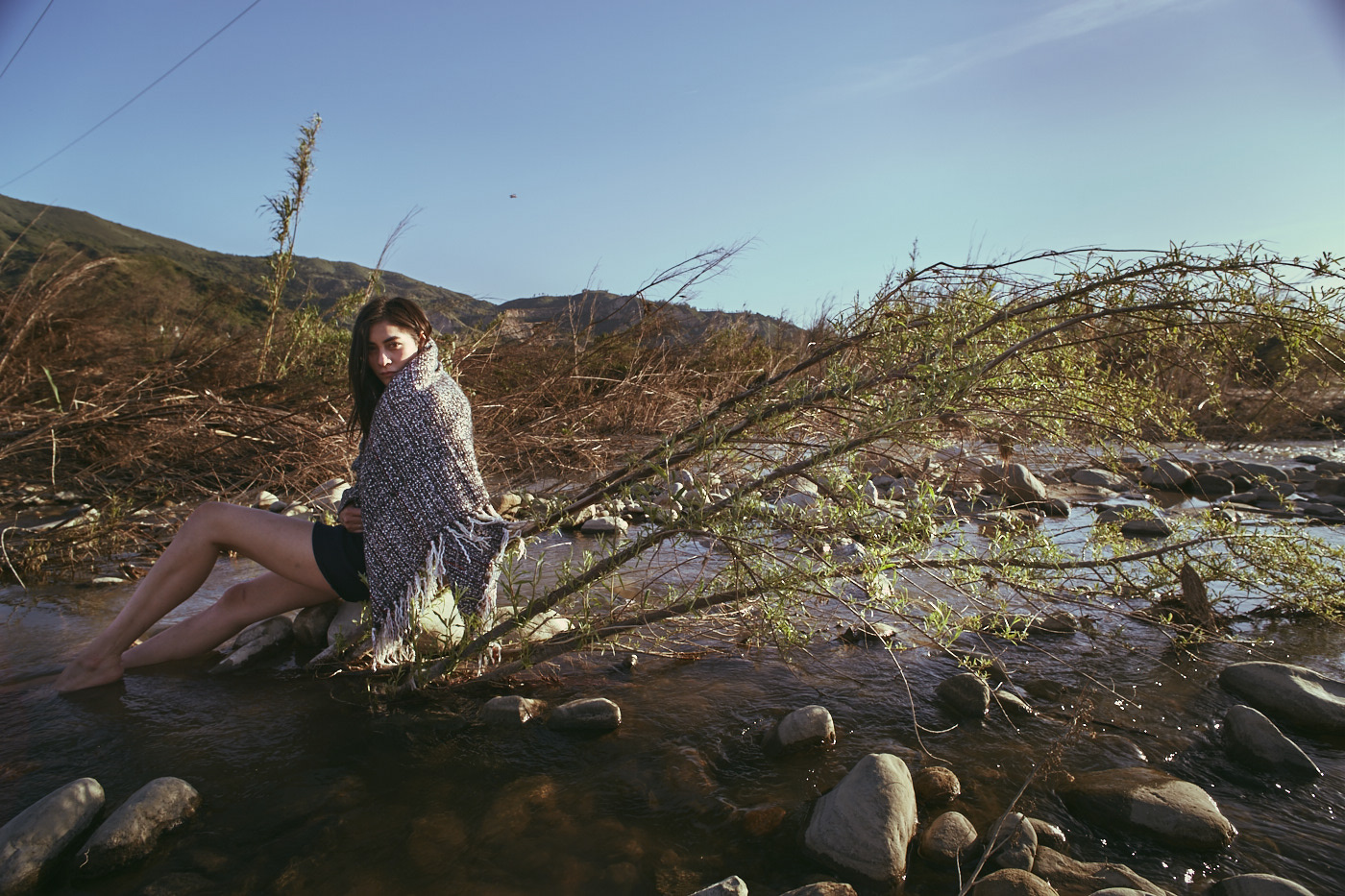 Beautiful woman sits in creek bed.  Photo by Modern Human