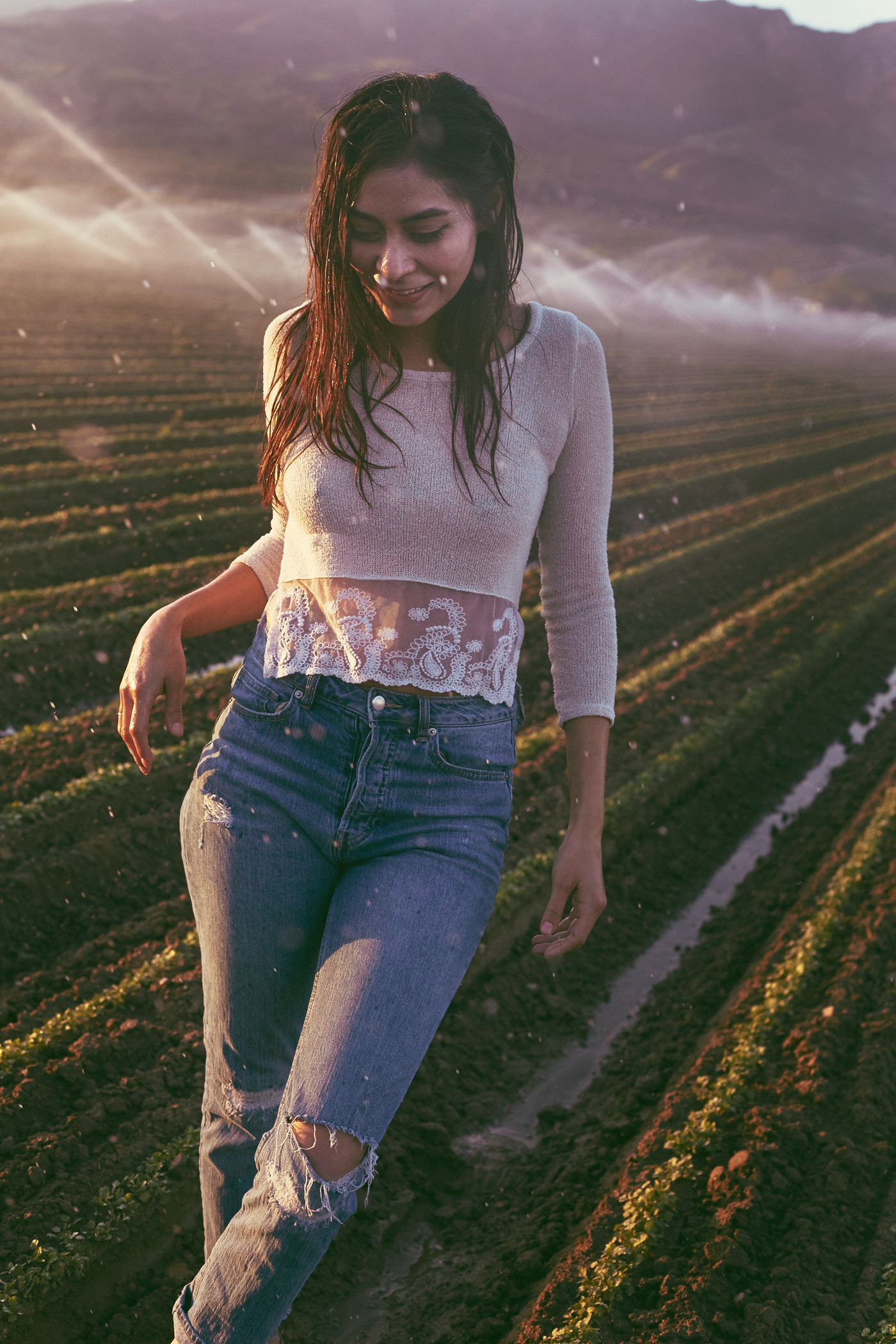 Beautiful woman bathes in sprinklers in field.  Photo by Modern Human