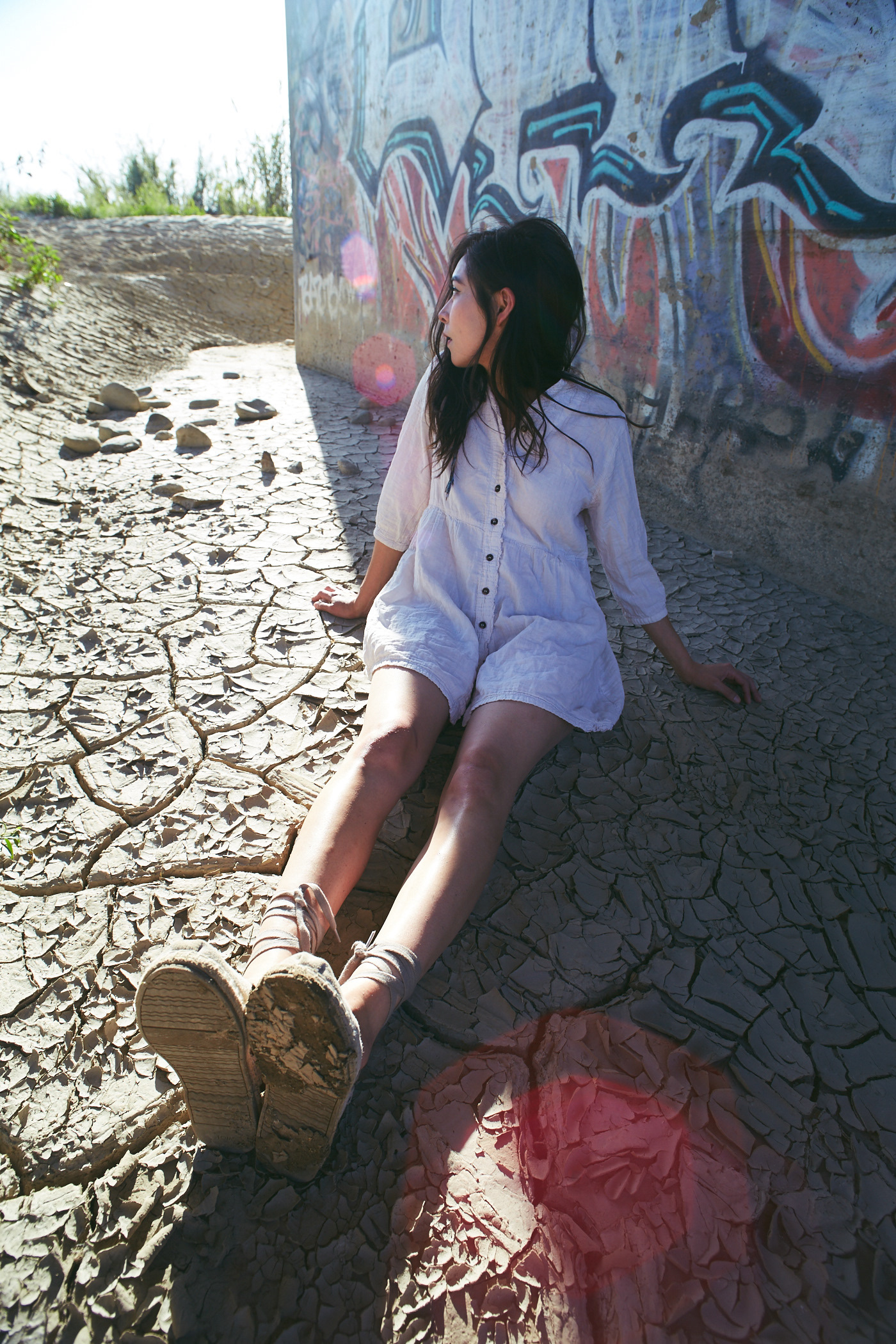 Beautiful woman sits on cracked dirt. Photo by Modern Human