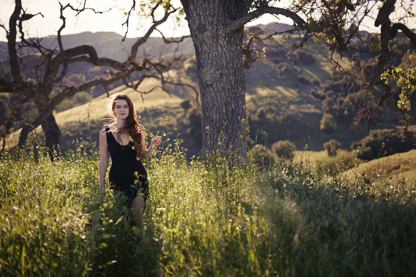 Beautiful woman walking rolling hills.  Wind blowing. Photo by Modern Human