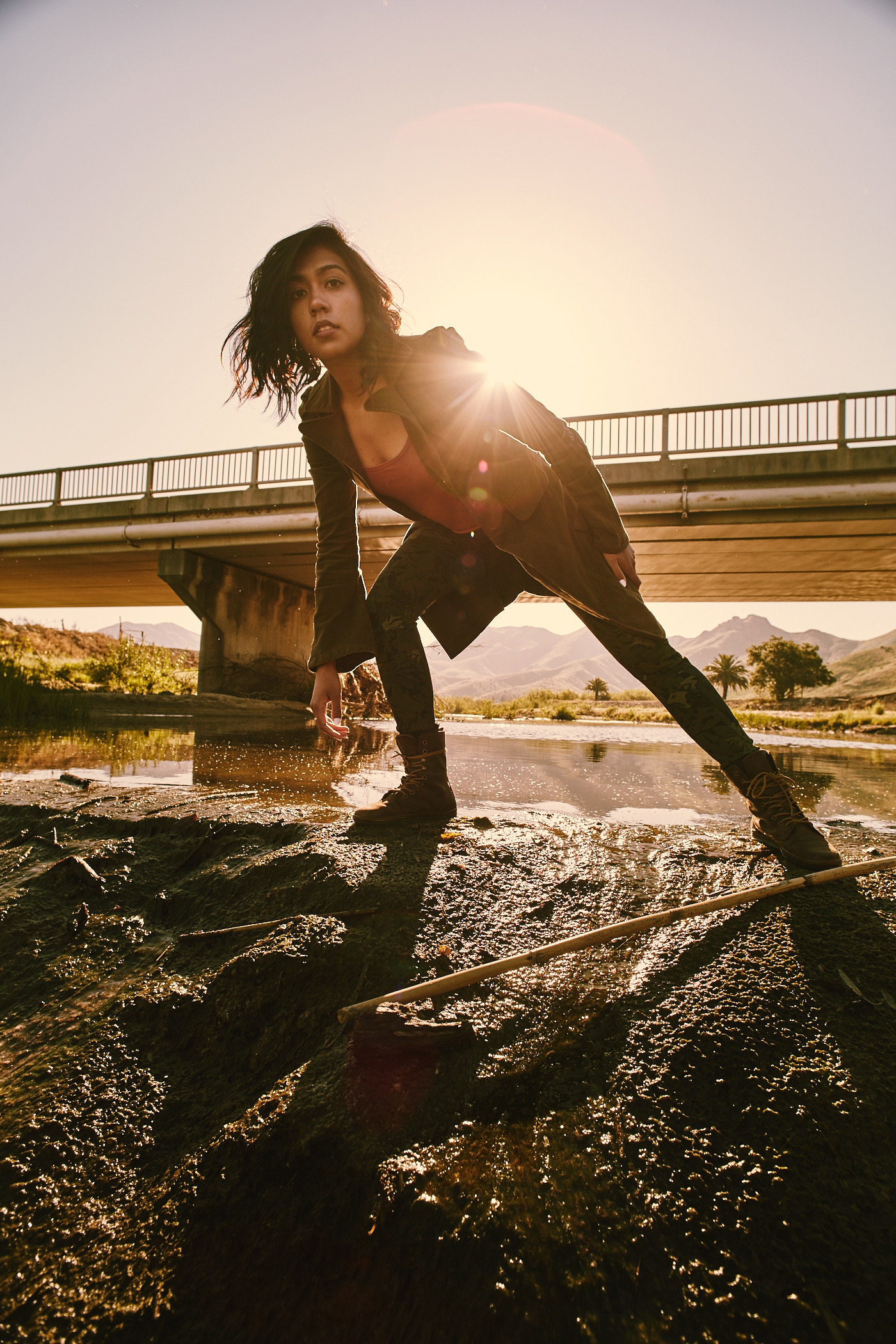 Beautiful girl standing on river bottom, under overpass.  Photo by Modern Human