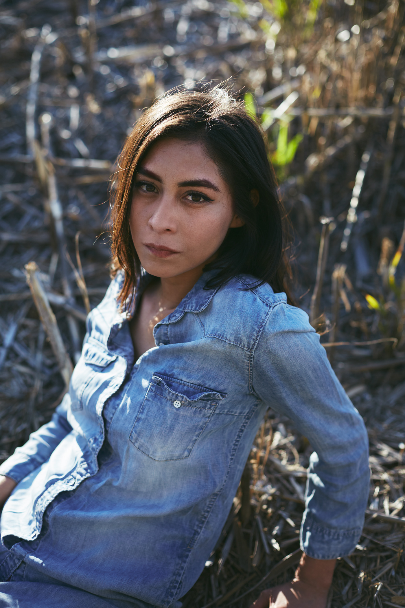 Beautiful woman sits on sticks.  Photo by Modern Human