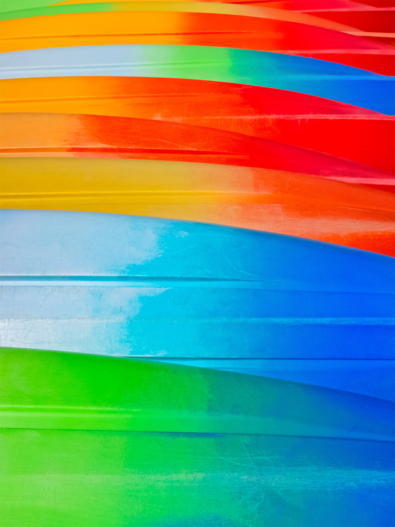 Abstract photograph of brightly colored red, blue, orange and green boat bottoms.