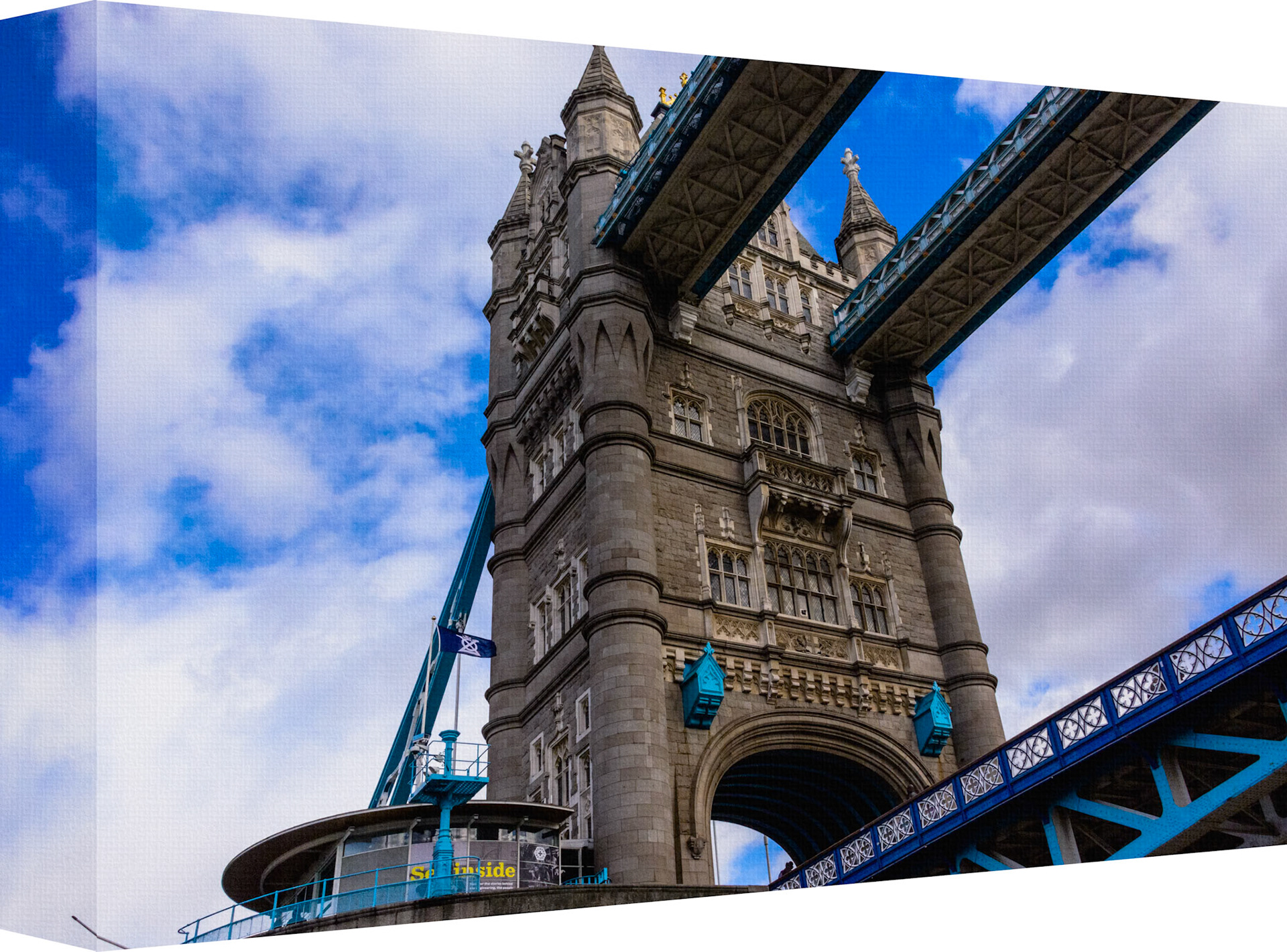 This stunning photograph captures a unique perspective of London’s iconic Tower Bridge. Taken from directly beneath one of the bridge’s towers, the image showcases the intricate stonework and steel framework against a backdrop of a bright, cloud-dotted sky. The composition highlights the grandeur and engineering marvel of Tower Bridge, emphasizing its historical significance and architectural beauty. The dynamic blue of the bridge contrasts beautifully with the soft white clouds, creating a sense of both strength and elegance. This artwork is perfect for those who appreciate architectural detail and the timeless charm of one of London’s most famous landmarks.