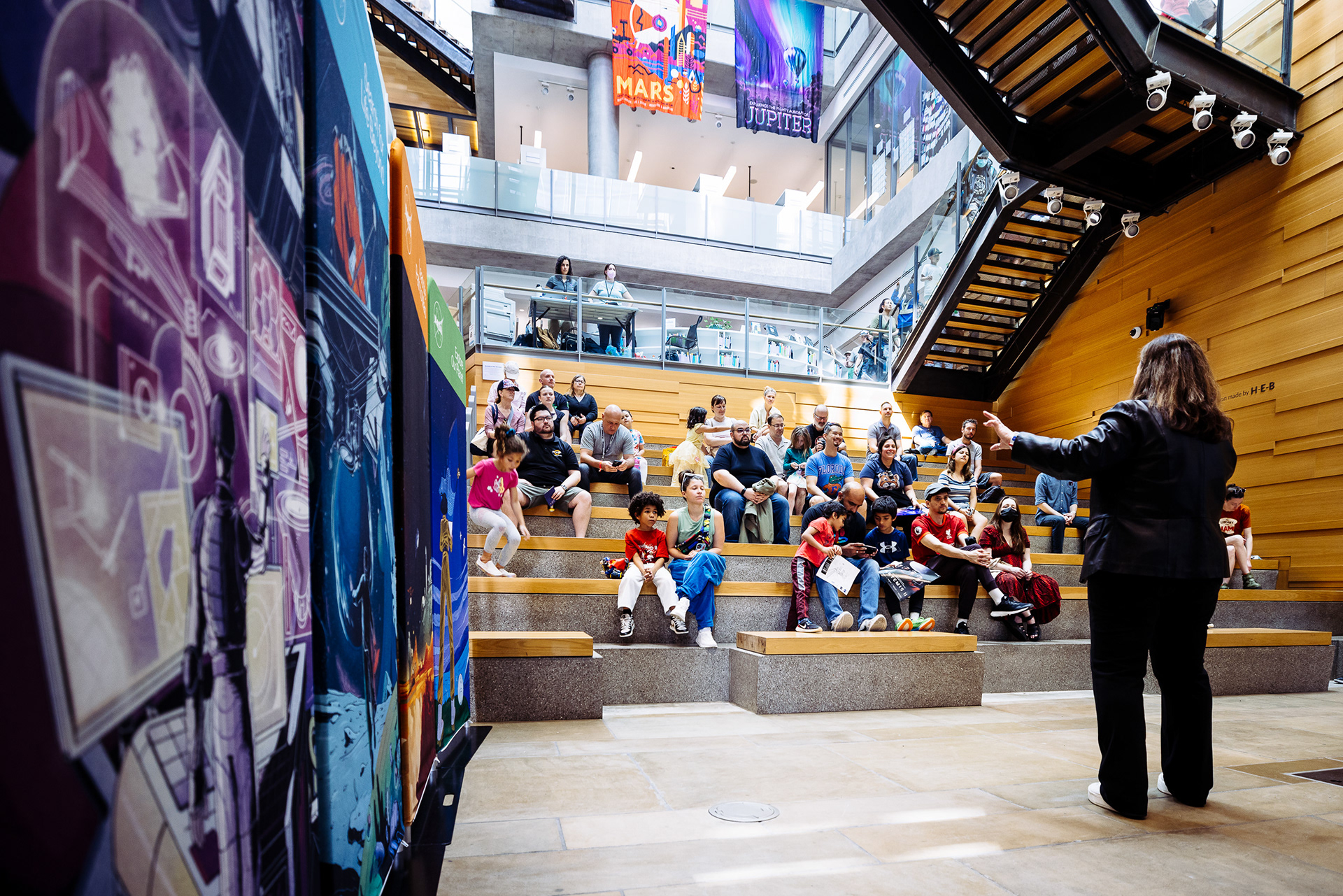 Crowd gathered in a mural-lined atrium at an event