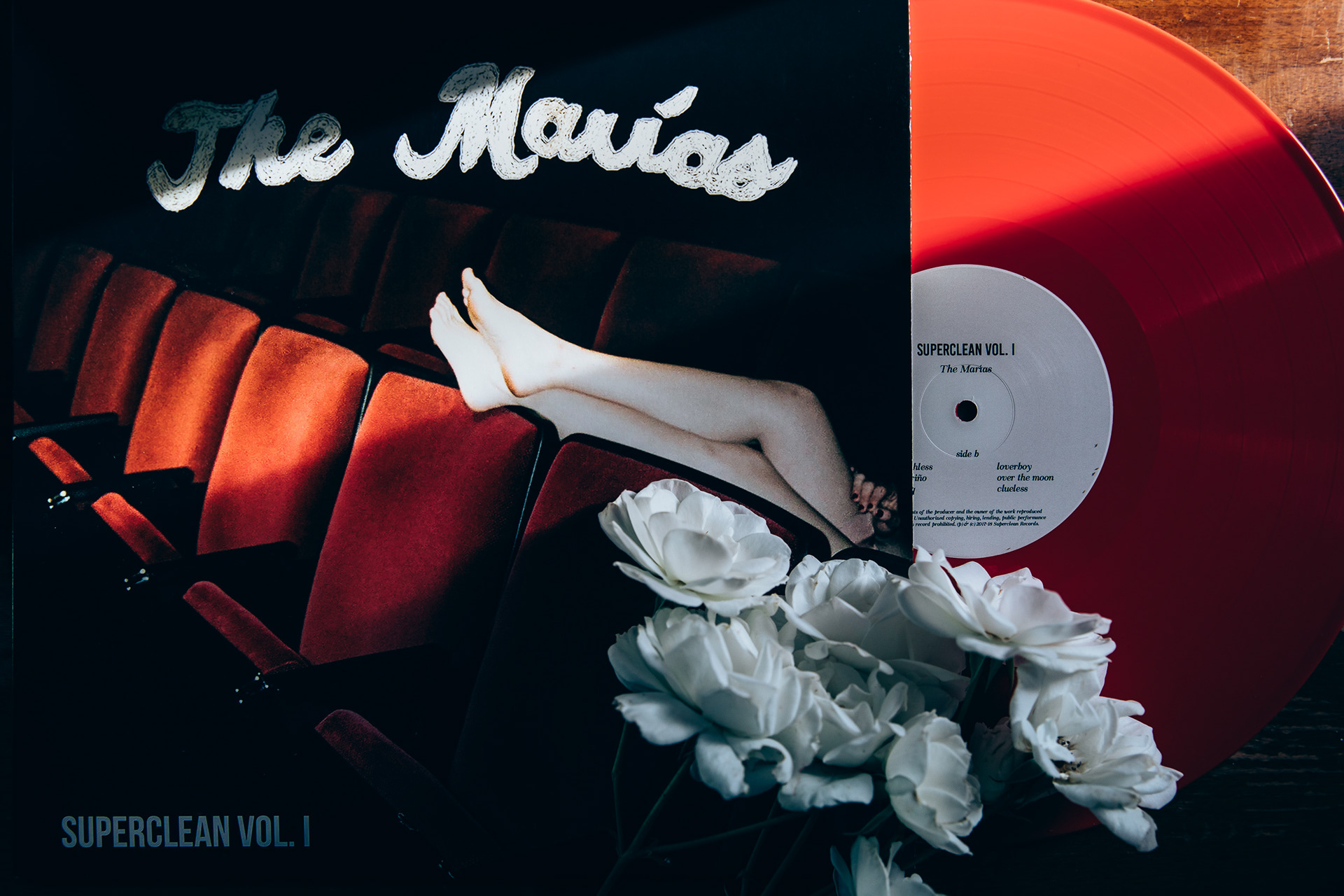 red vinyl record beside an album sleeve, vinyl record photography in San Antonio by Chris Stokes