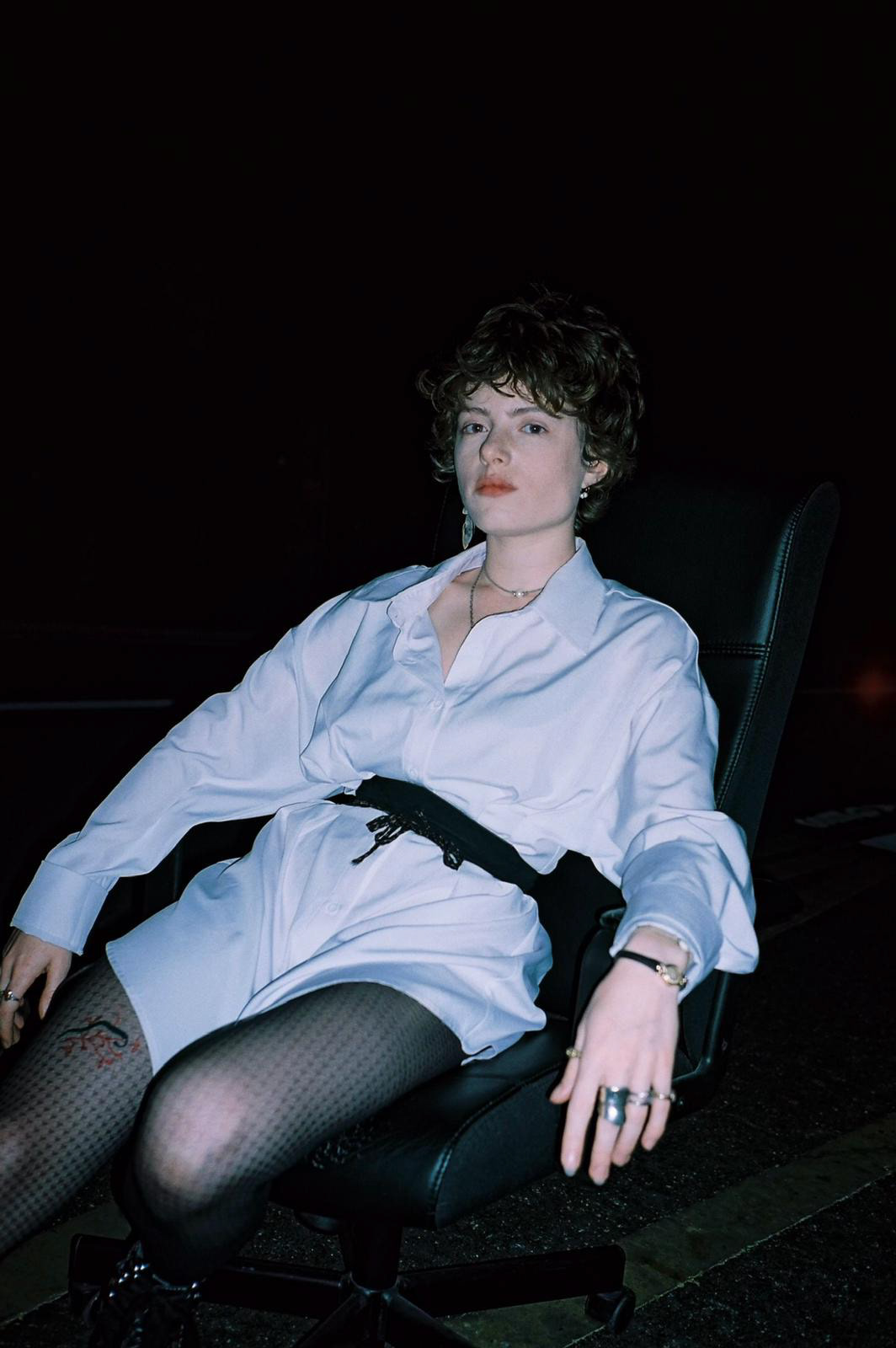 fashion portrait of young woman sitting on a chair on the street by night