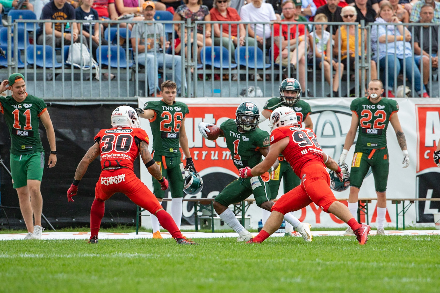 1 Markell Castle (grün) gegen 30 Jamaal White und 92 Adam Roszkowski (rot von links) im Spiel der Kiel Baltic Hurricanes (grün) gegen die Braunschweig New Yorker Lions (rot) am 03.08.19 im Kilia Stadion in Kiel