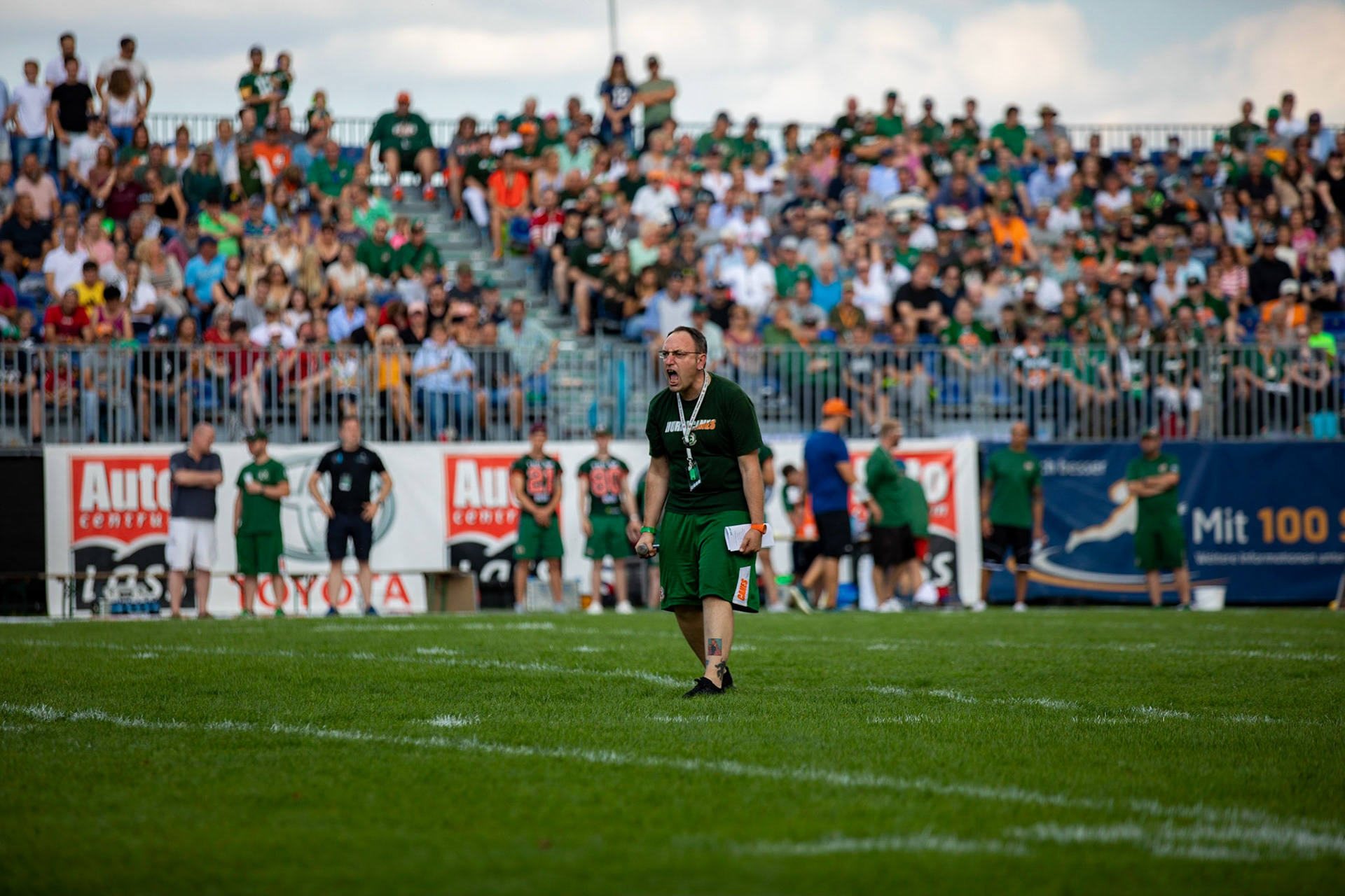 Kurzer Technik-Ausfall beim Einlaufen der Mannschaften störte den Stadionsprecher nicht. Er brüllte einfach. im Spiel der Kiel Baltic Hurricanes (grün) gegen die Braunschweig New Yorker Lions (rot) am 03.08.19 im Kilia Stadion in Kiel