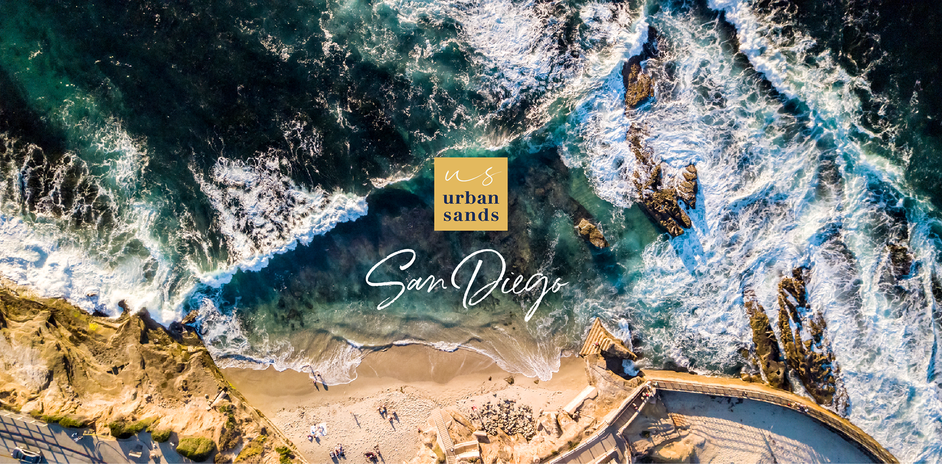 Urban Sands logo in gold square and San Diego (in brand script) set on photo of La Jolla Cove (designs by Kat Vochoska).