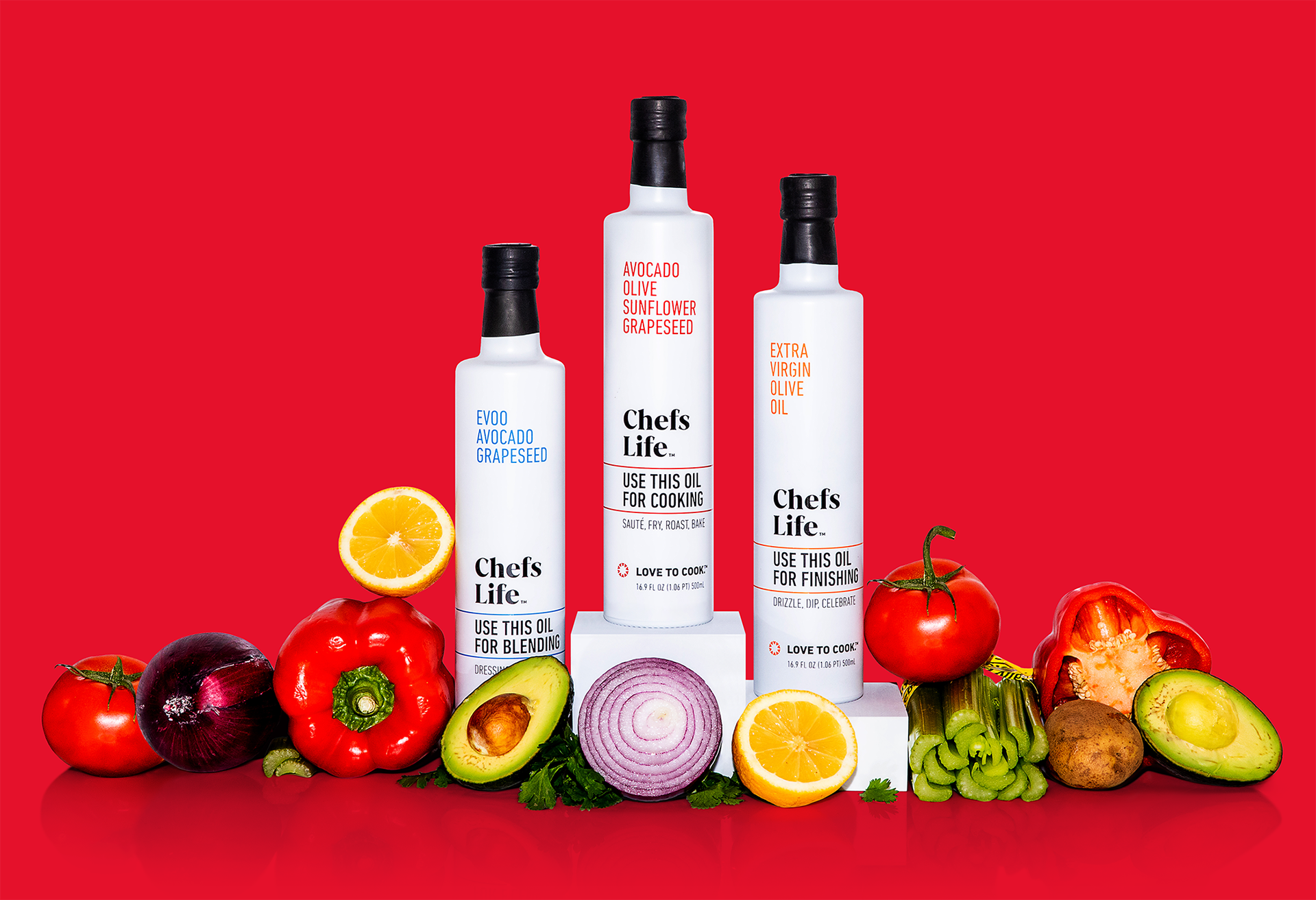Chefs Life™ oils for cooking, blending, and finishing surrounded by assorted, colorful vegetables (designs by Kat Vochoska).