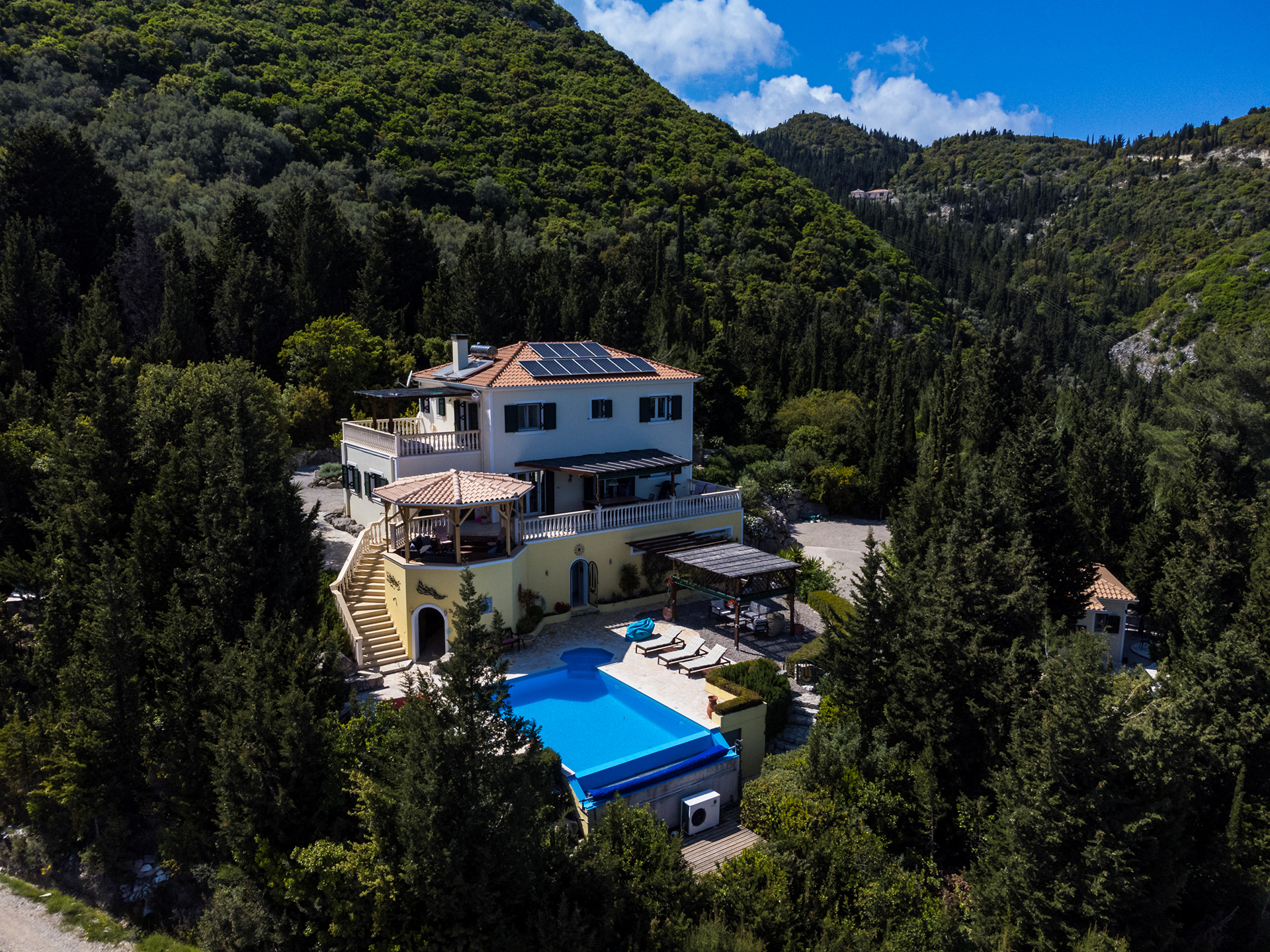 Aerial view of Villa Gabriella Lefkada, a luxury hillside villa with pool surrounded by forest on the island of Lefkada, Greece.