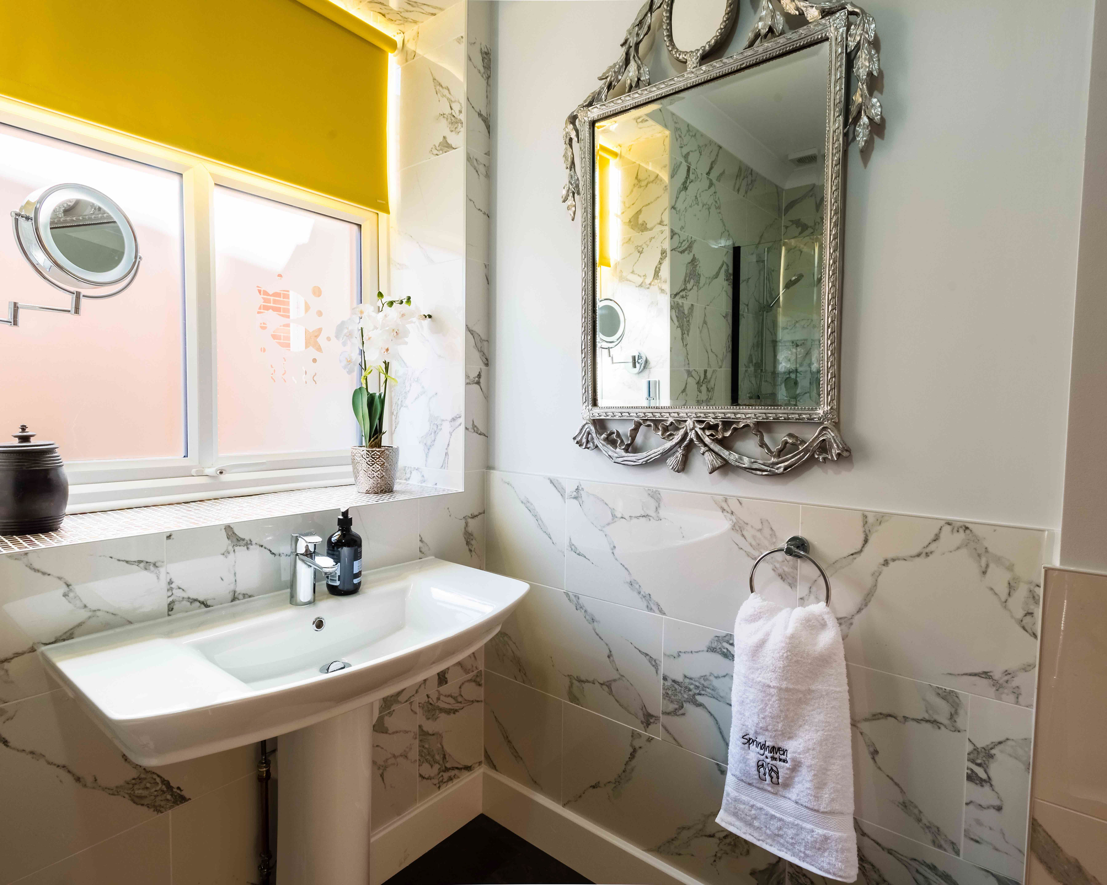 Marble bathroom with statement mirror and warm morning light