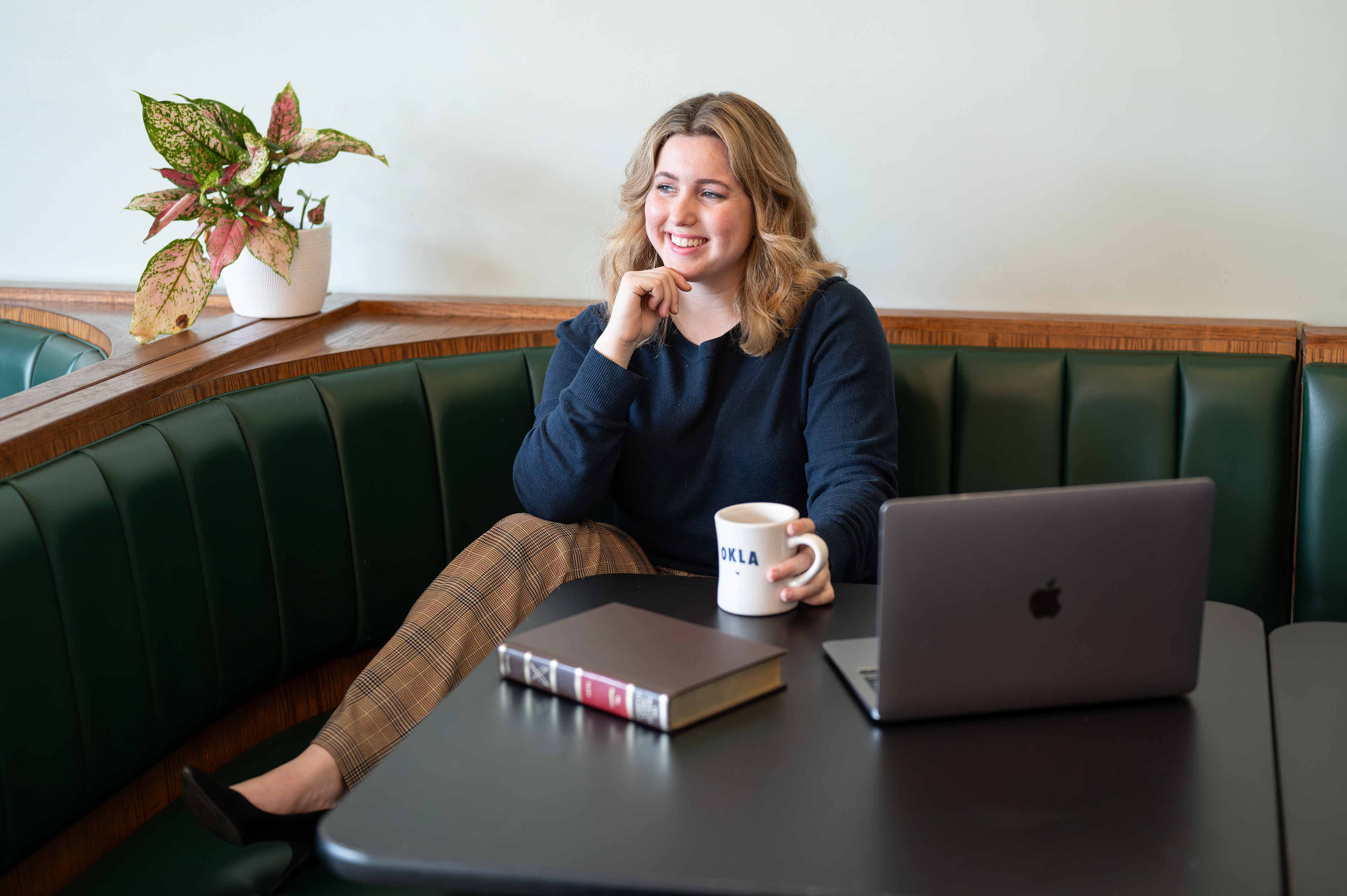 young women with laptop, mug, and a book. 