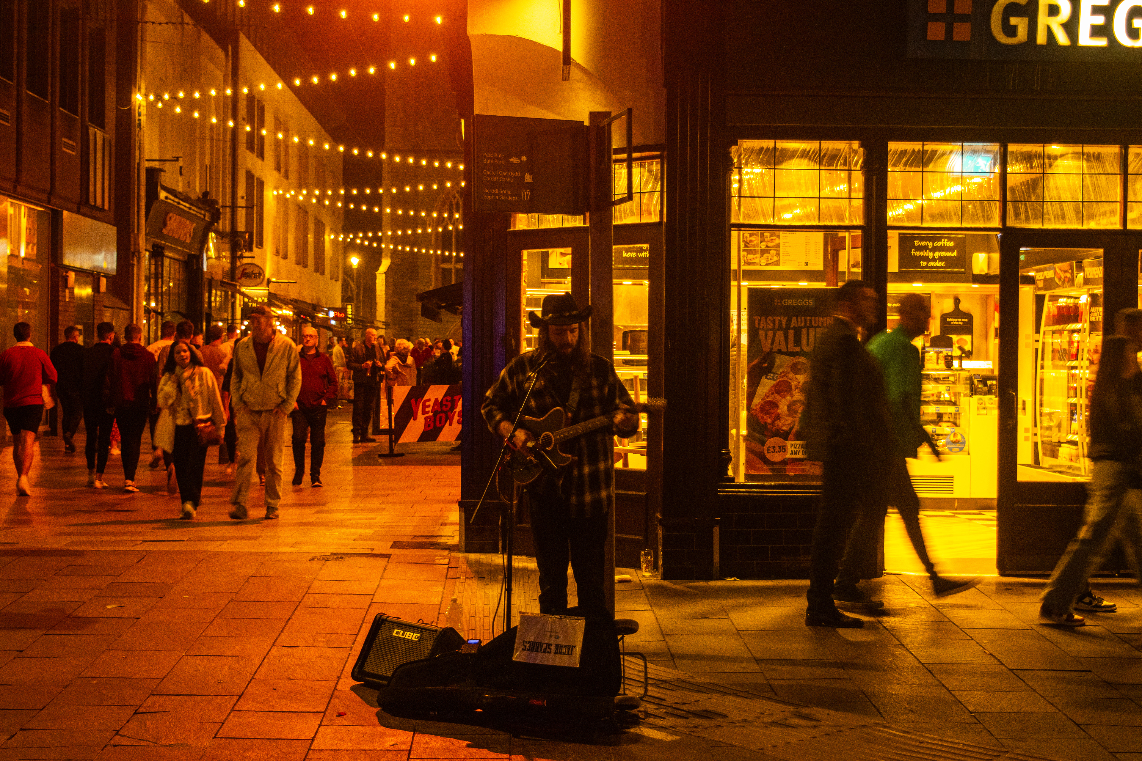 'Busking'. A man sings and plays his guitar on the street.