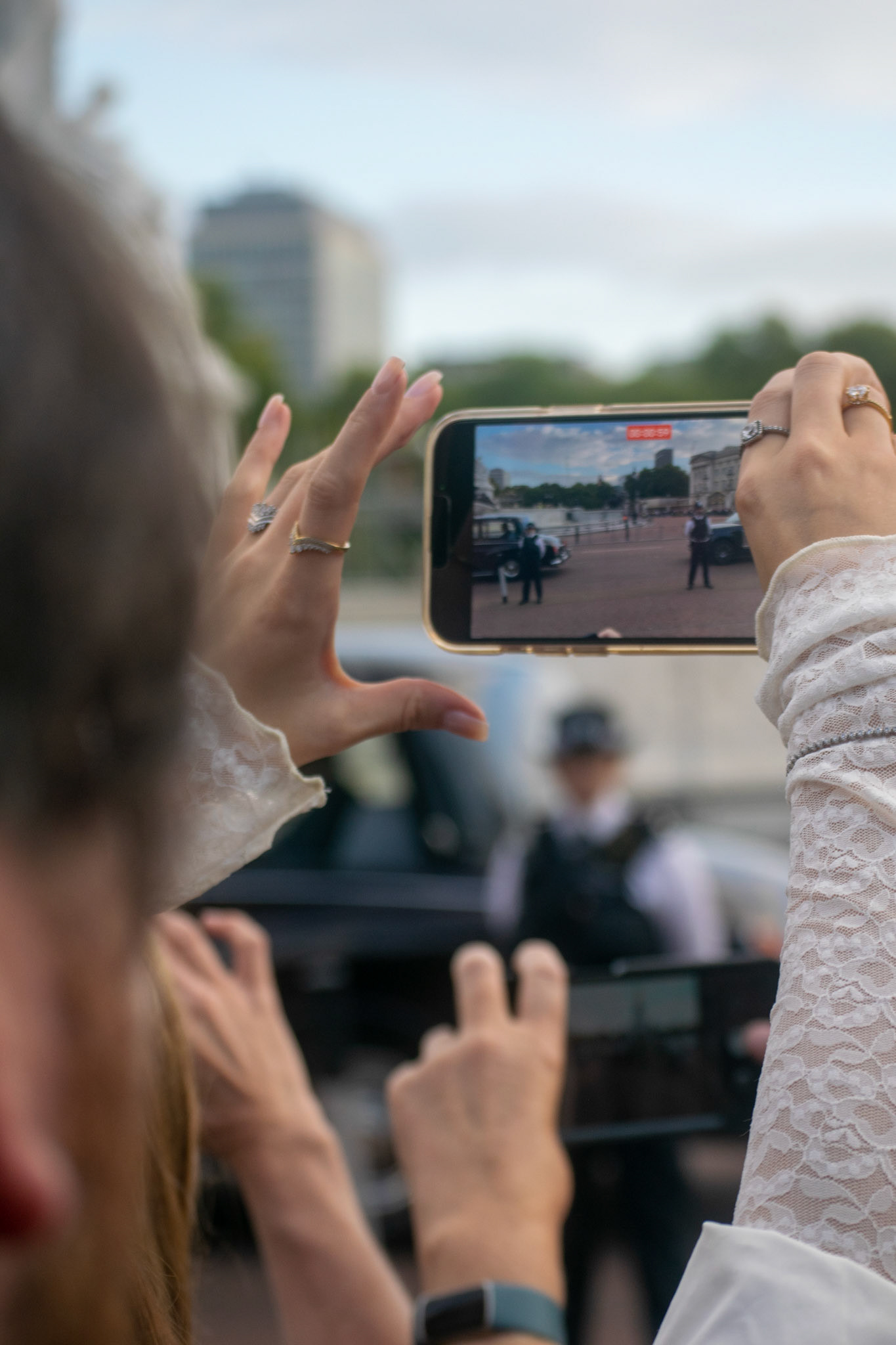 A lady shoots a video of the royal convoy as it passes through the crowd.