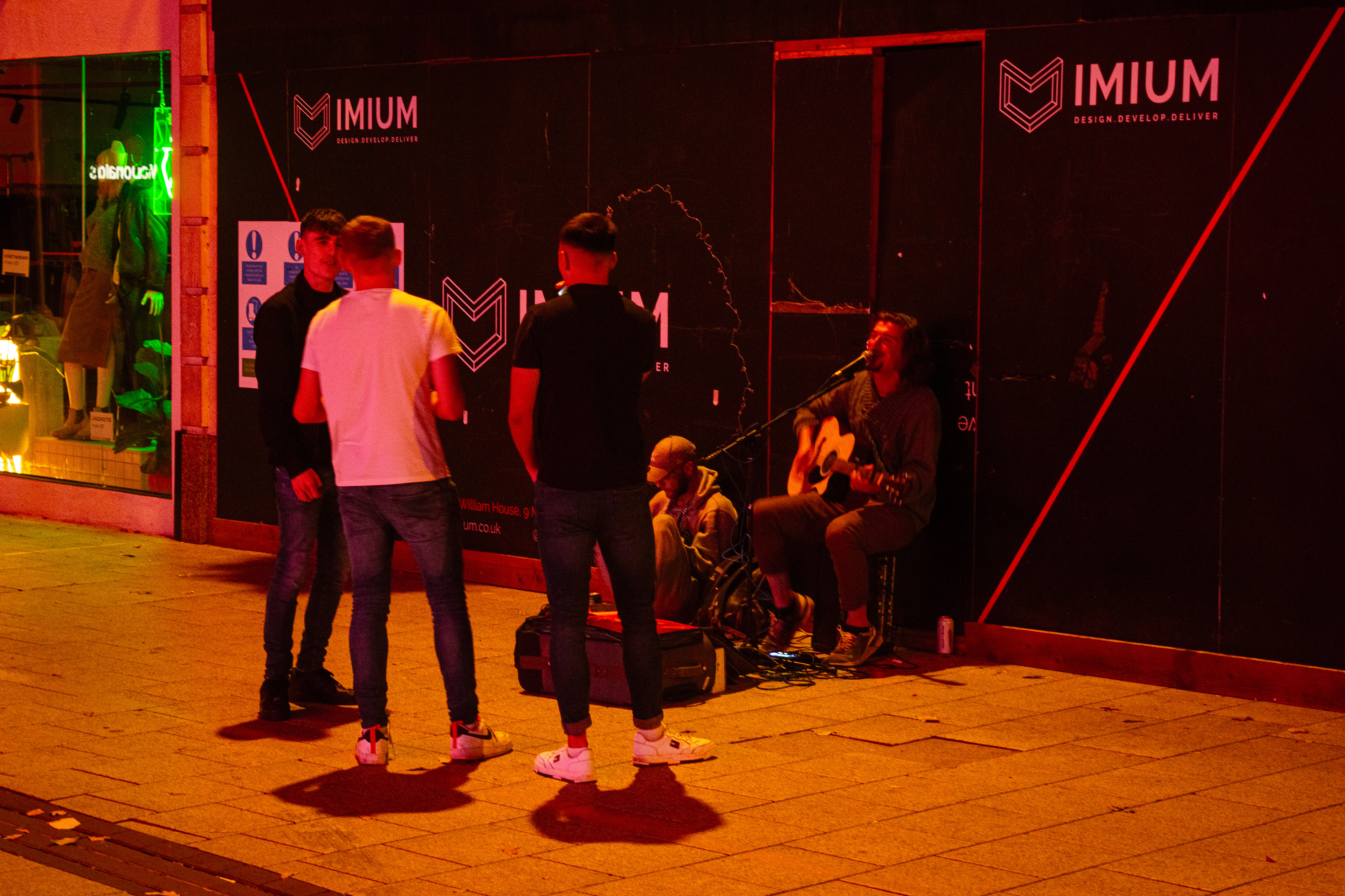 In the image, three lads excitingly request a song from the street performer. Cardiff is a city filled with students, owing to the presence of three major universities. The month of September welcomes an influx of students not only from the UK but from the far corners of the world. Maybe these three boys moved together, or they met in Cardiff itself; either way, it will be the start of a fun and adventurous uni journey, and they celebrate it by dancing to the song. 