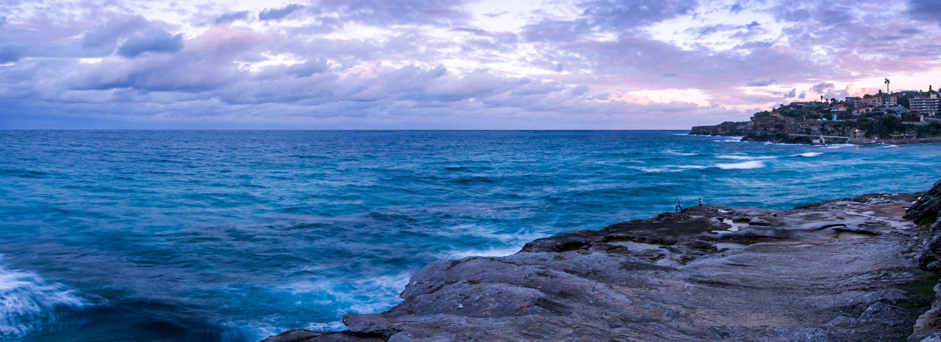 A panorama, showing a couple overlooking Bronte Beach