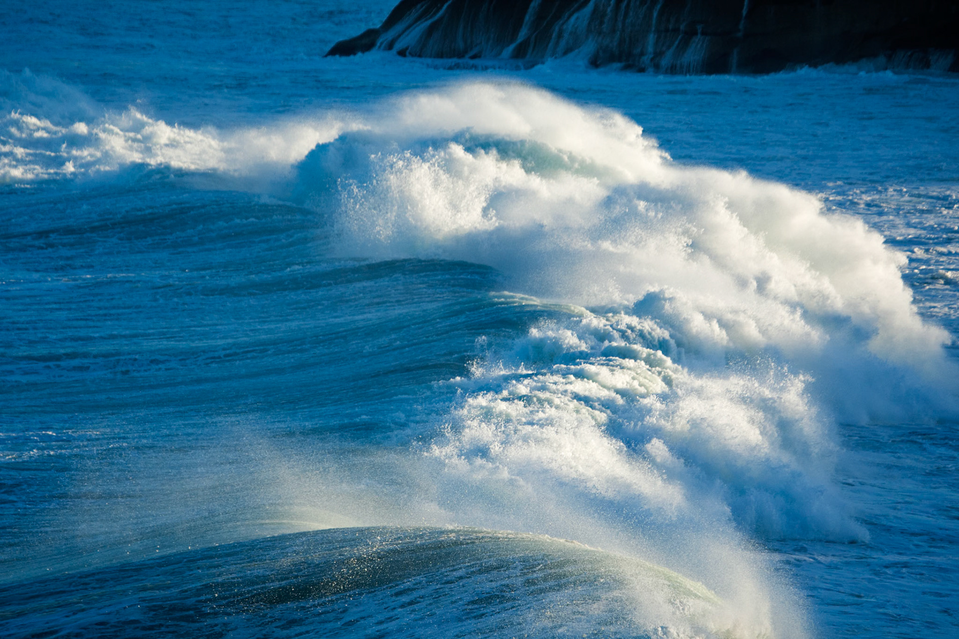A wave breaking in a spot of sun taken from the cliffs overlooking Mackenzies Bay during a period of big seas- huge surf and spray.
