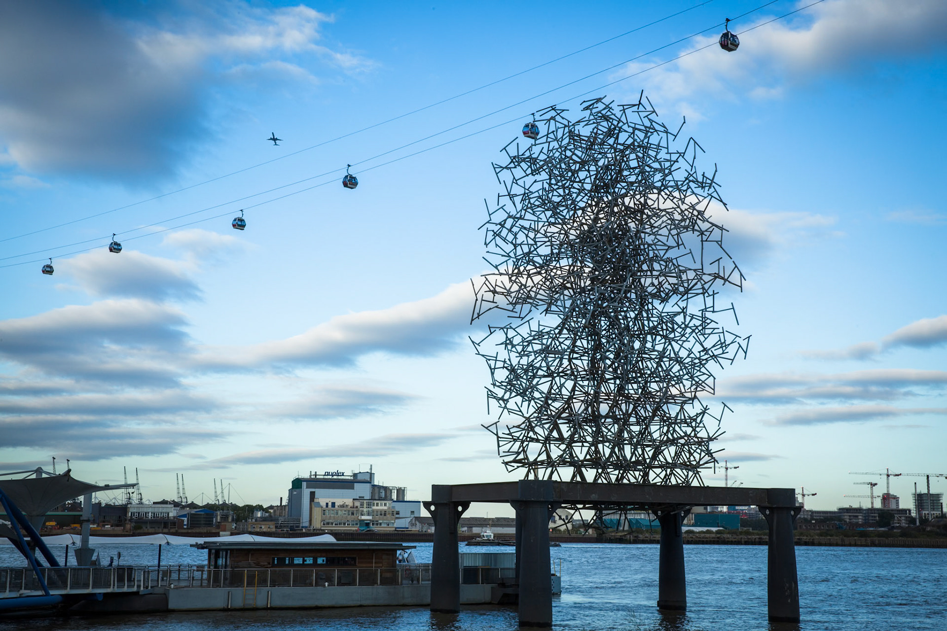Aeroplane, Emirates Air Line cable cars and the Quantum Cloud sculpture by Antony Gormley. Greenwich Peninsula, South East London