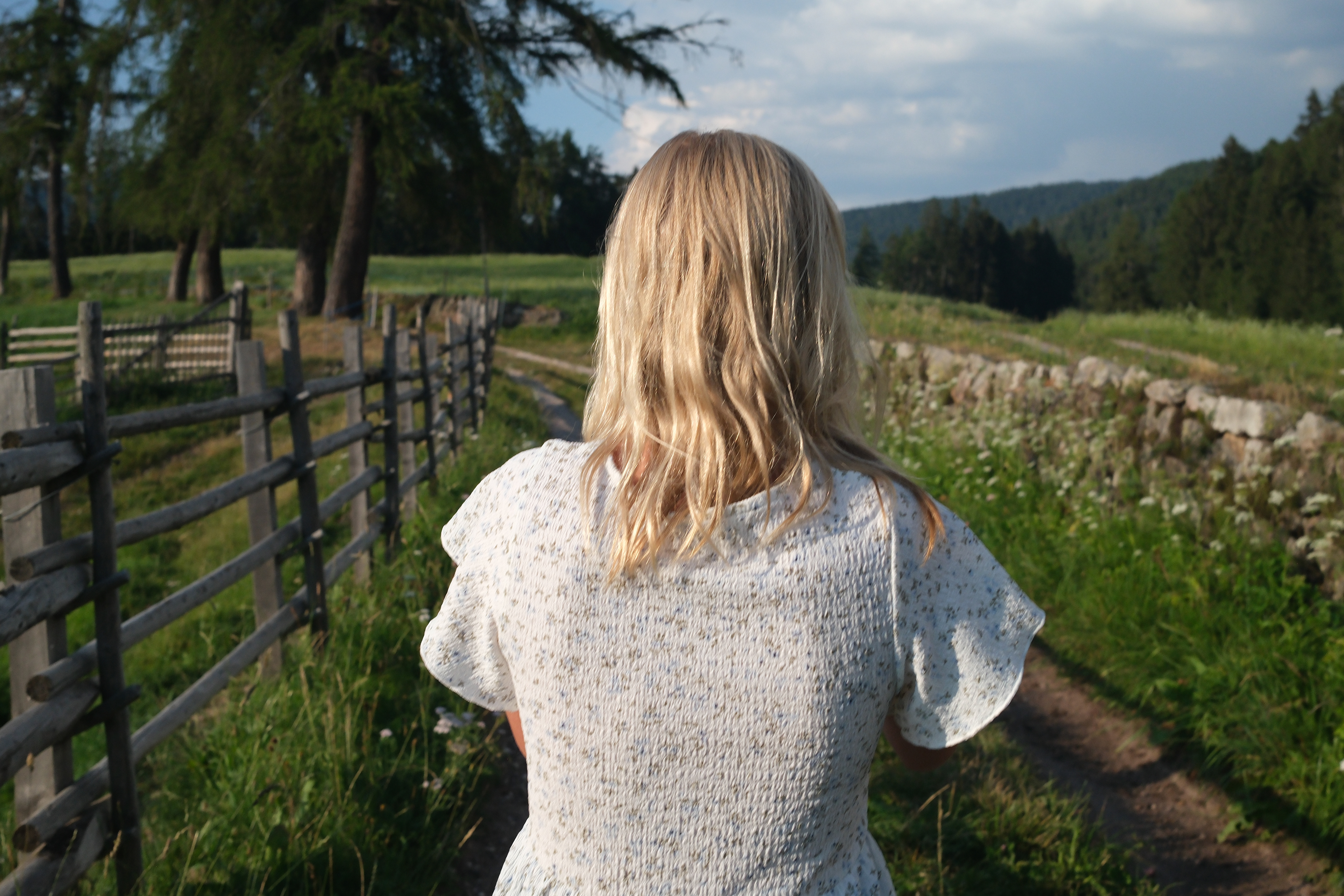 zirmerhof hotel in Sudtirol, blonde girl walking in the fields from the back