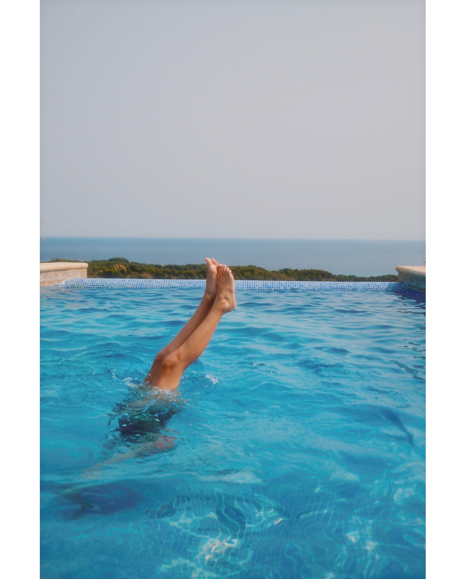 legs coming out of the water, diving in a infinity pool